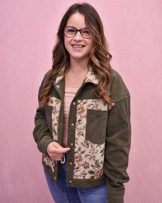 Woman wearing a green jacket with floral patterns on a pink background