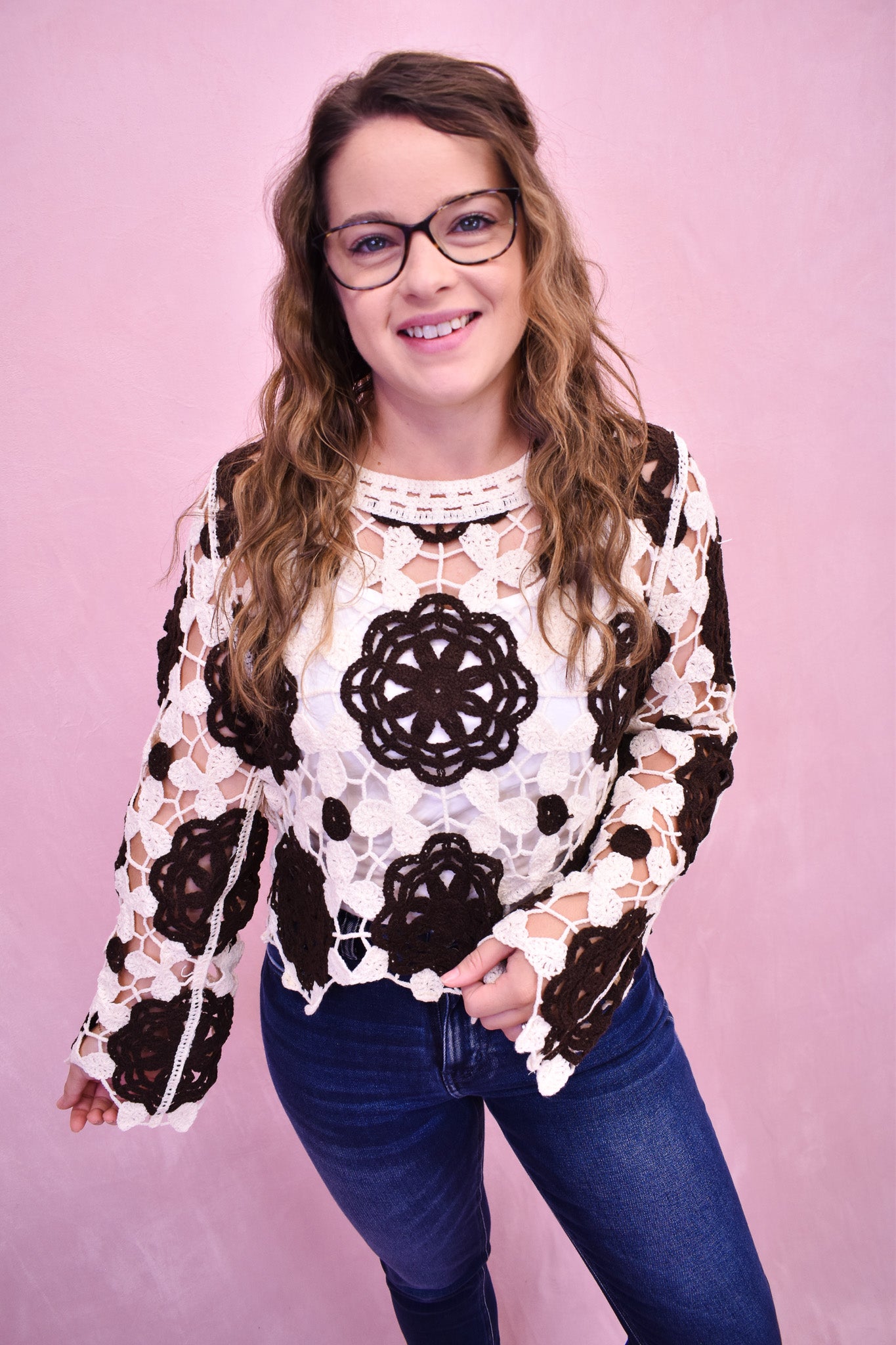 Woman wearing a black and white patterned top against a pink background