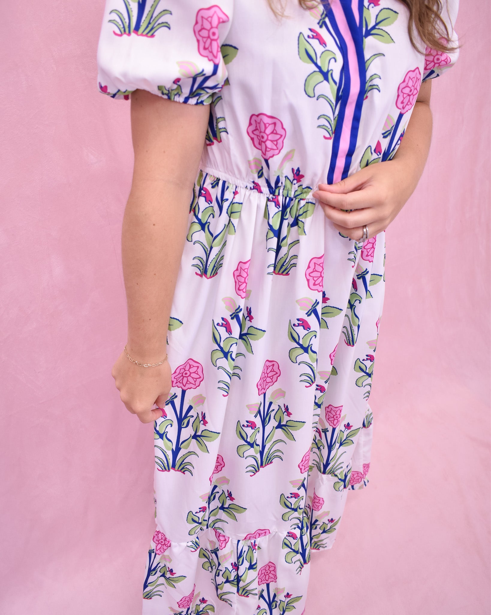 Person wearing a floral dress with a pink background