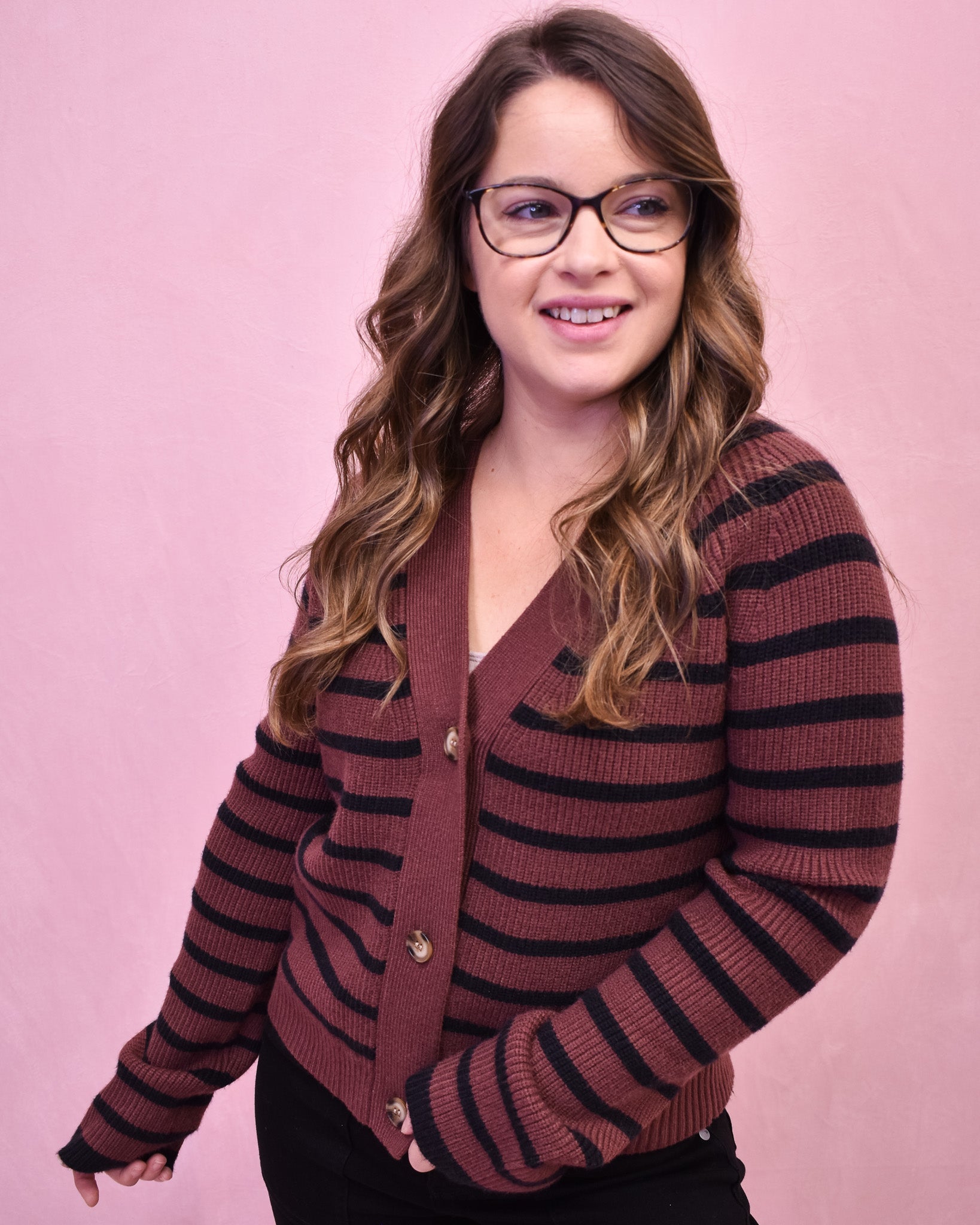 Woman wearing a striped sweater against a pink background