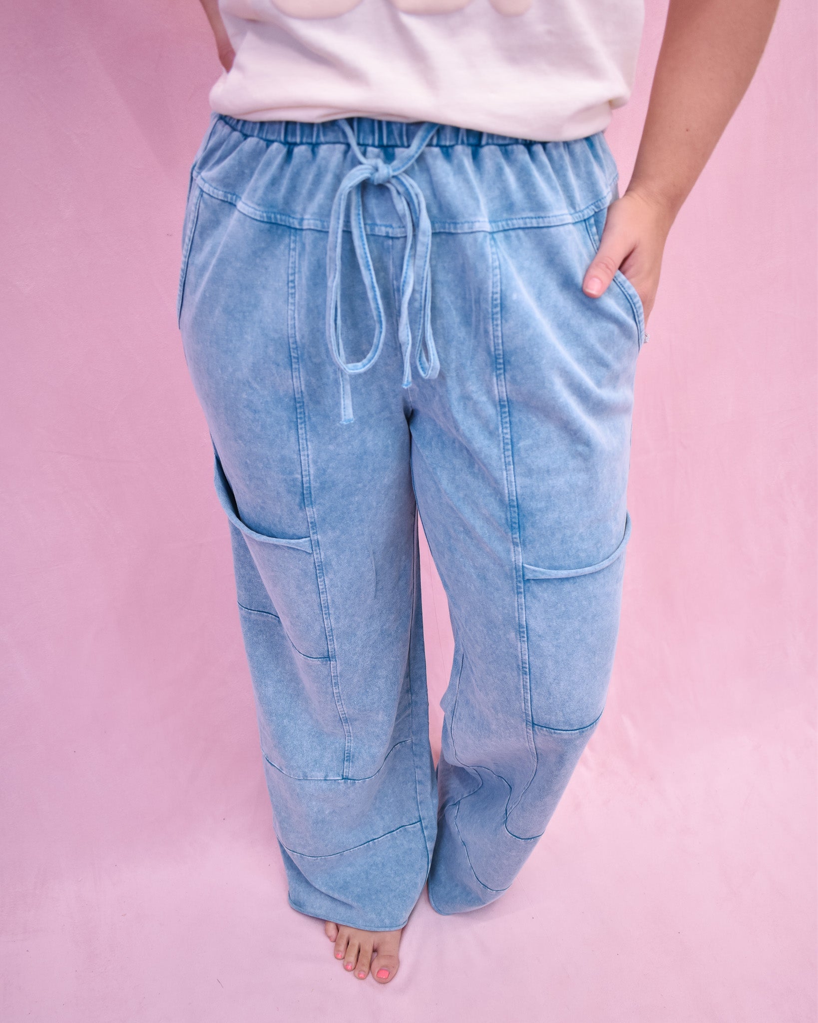Light blue denim jogger pants worn by a person on a pink background