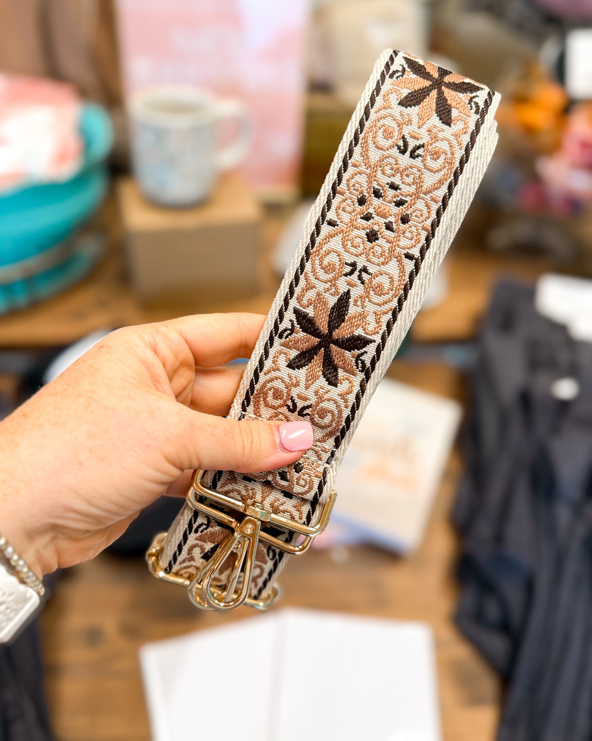 Hand holding a decorative belt with intricate patterns in a store setting