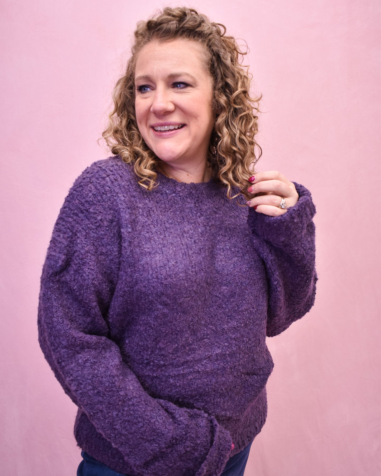 Person wearing a purple sweater against a pink background