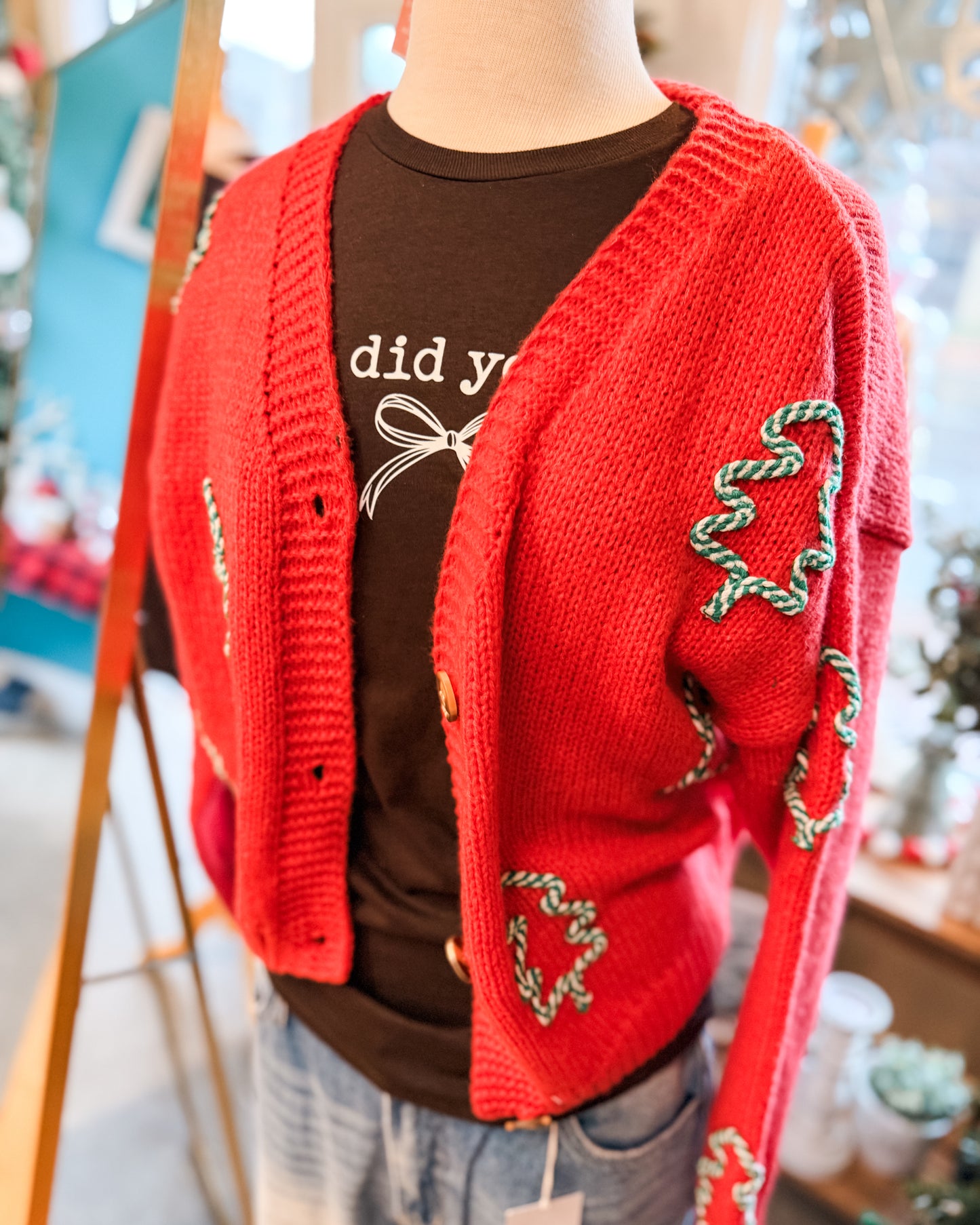 Red knitted cardigan with decorative patterns over a brown shirt.