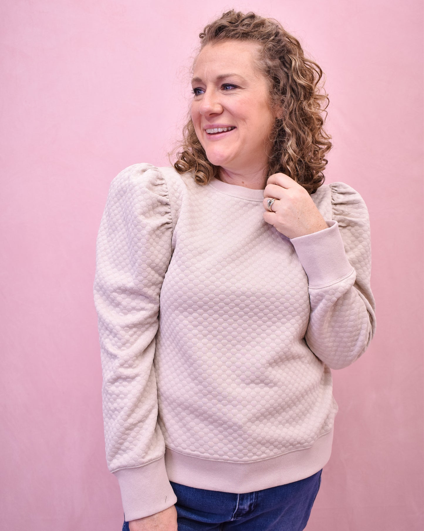 Woman wearing a textured light pink sweater against a pink background