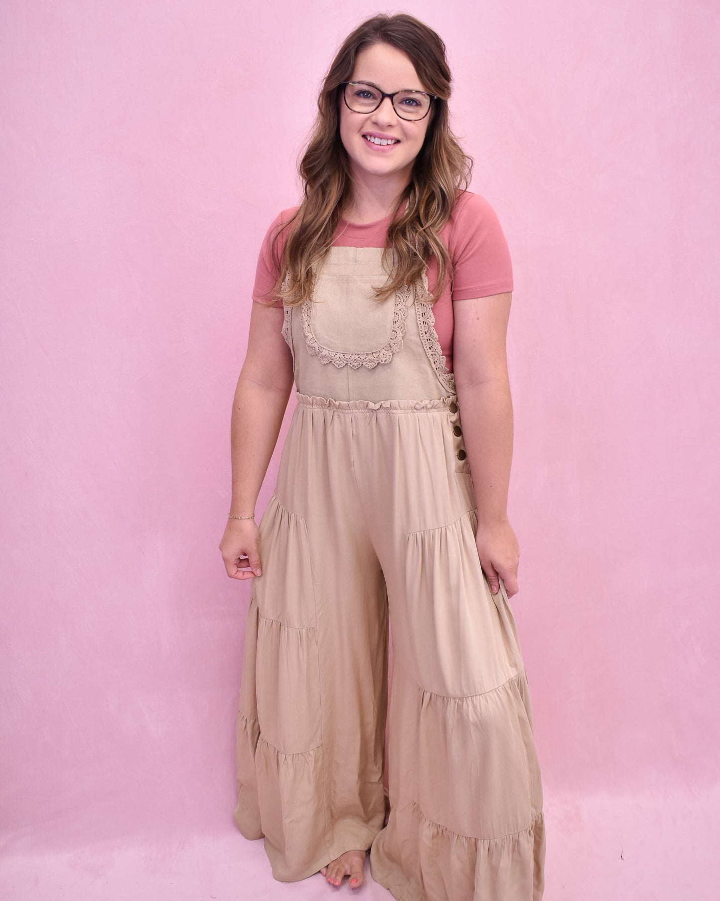 Woman wearing a beige dress over a pink shirt against a pink background