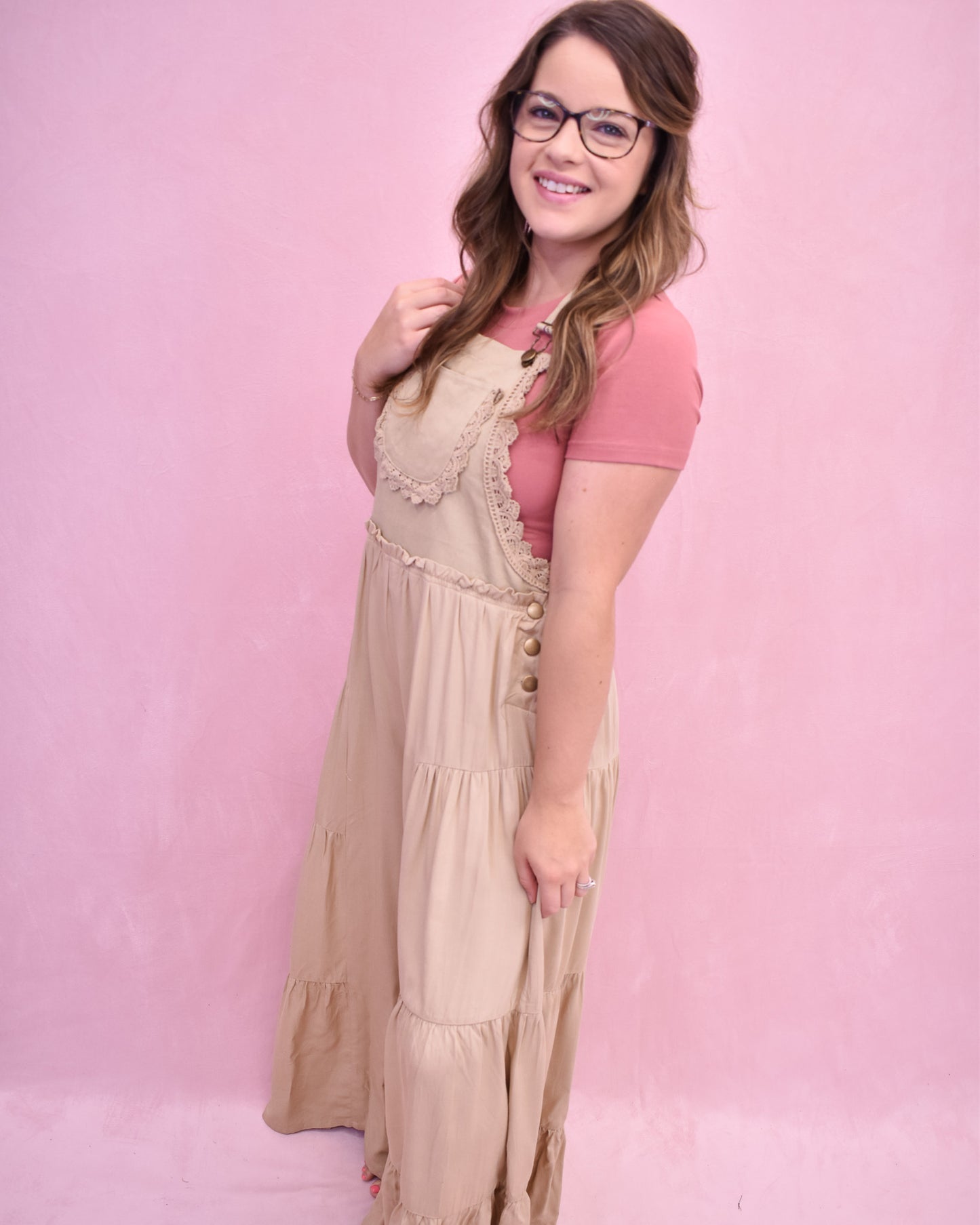 Woman wearing a pink top and beige dress against a pink background