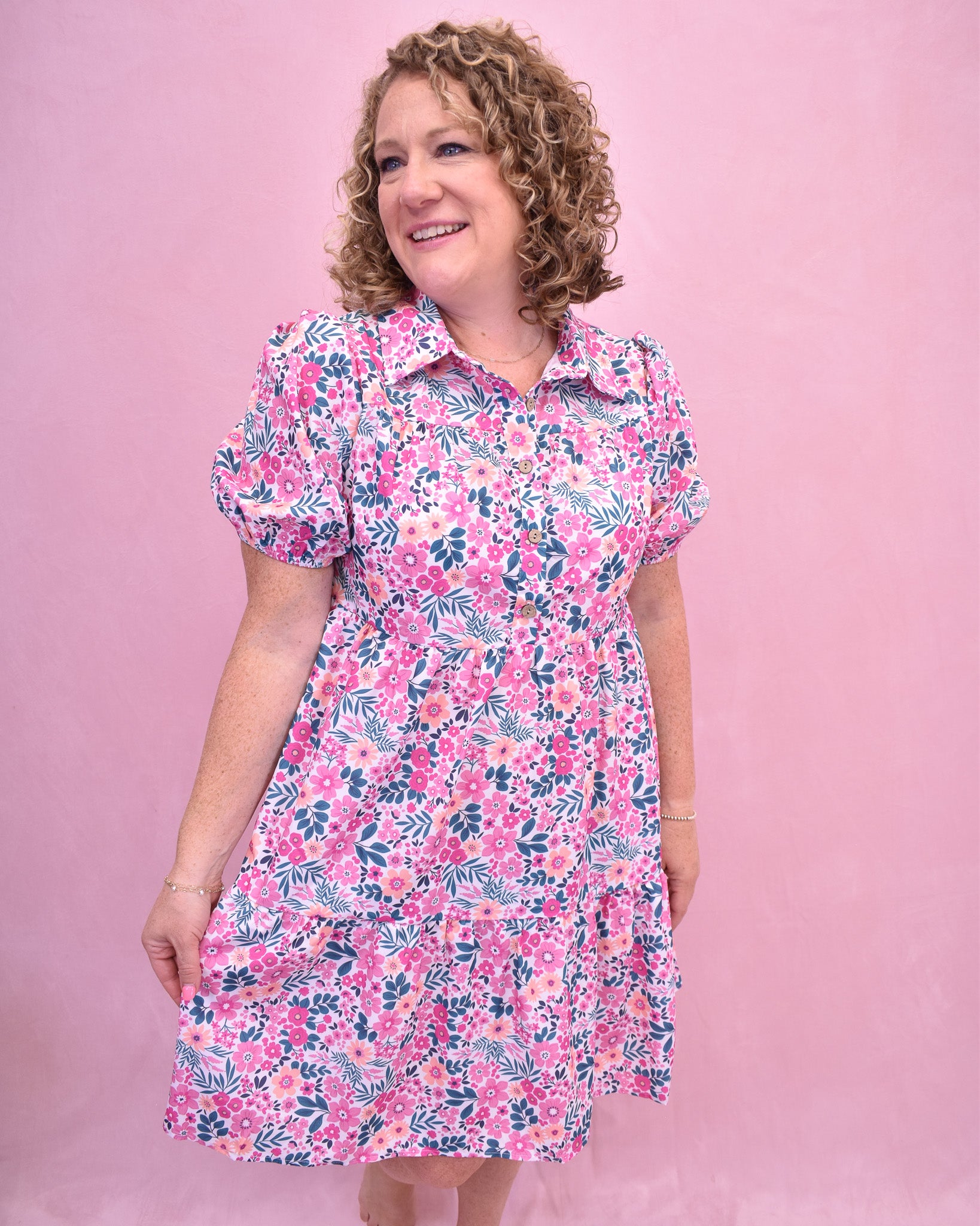 Woman wearing a floral dress against a pink background