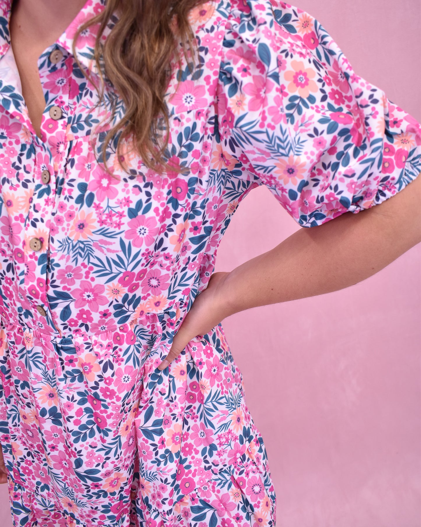 Person wearing a pink floral dress against a pink background