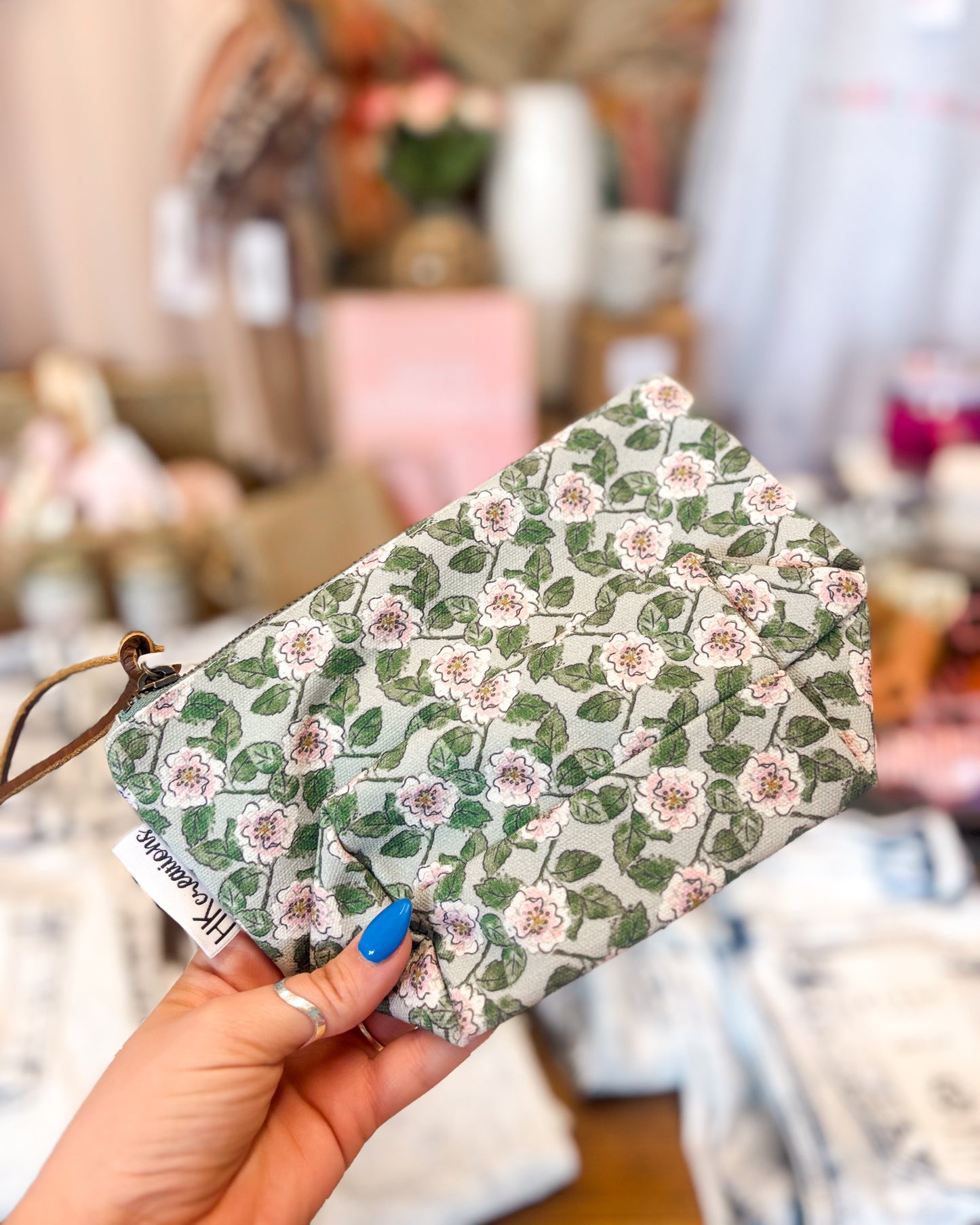 Floral-patterned pouch held by a hand with a blurred background