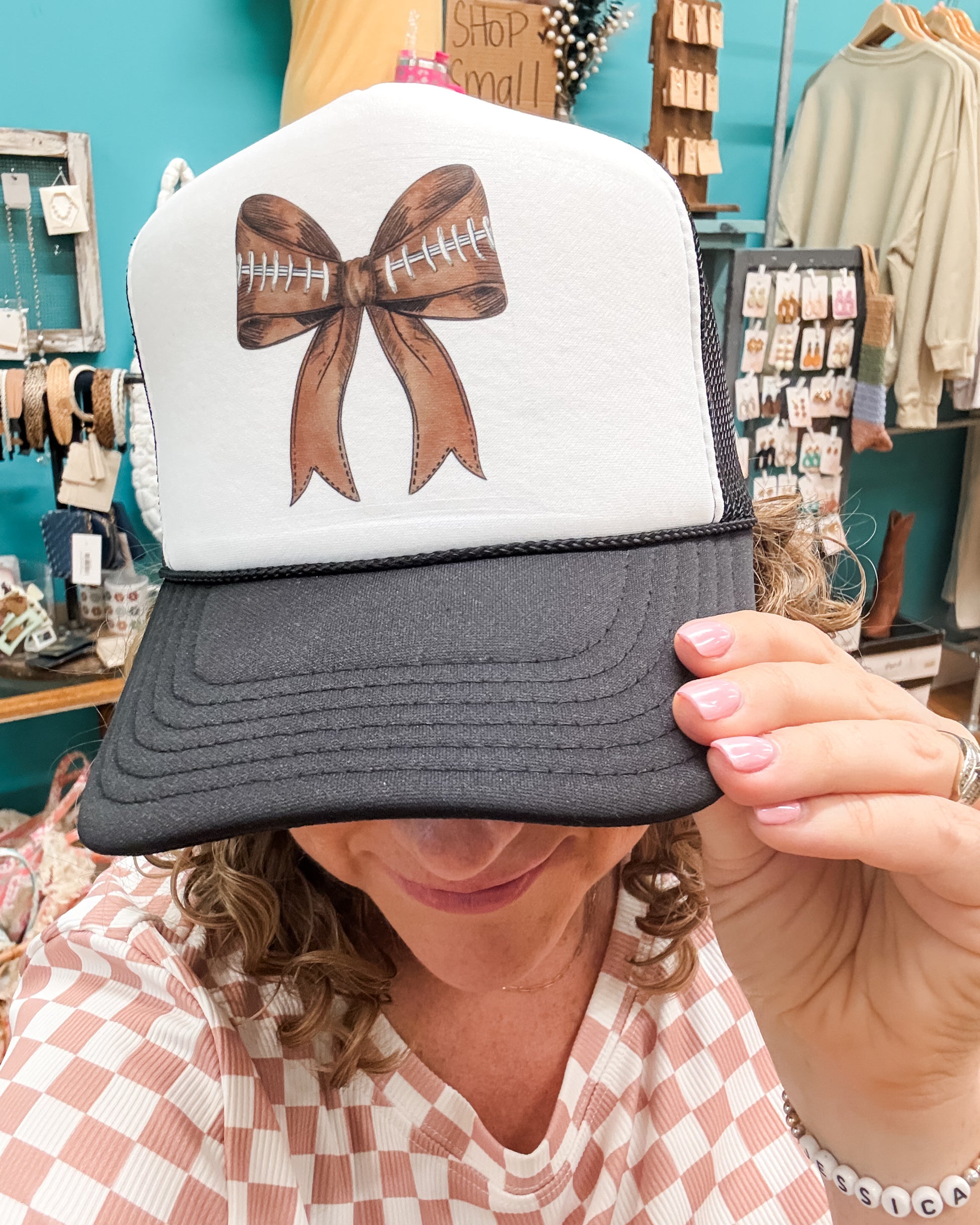 Person wearing a cap with a brown bow design in a store setting
