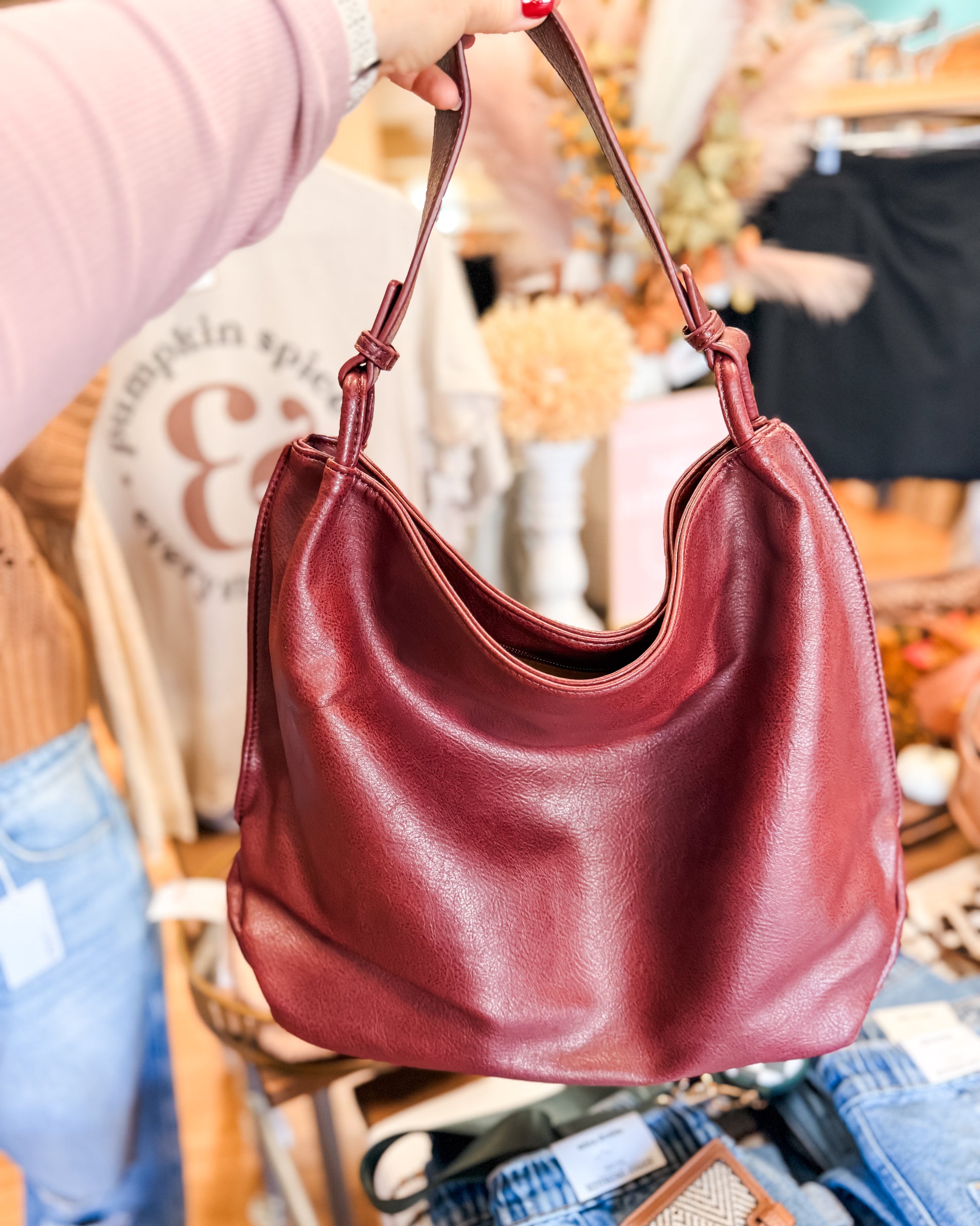 Red handbag held by a person in an indoor setting with blurred background