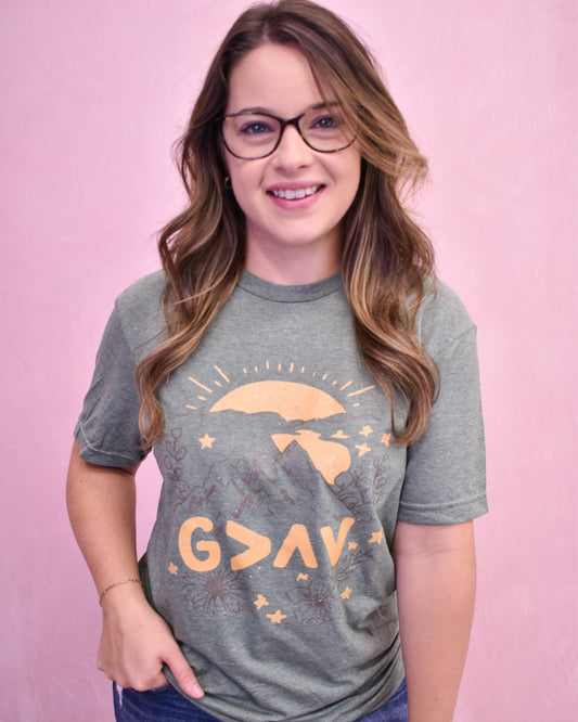 Person wearing a gray t-shirt with a design and text on a pink background