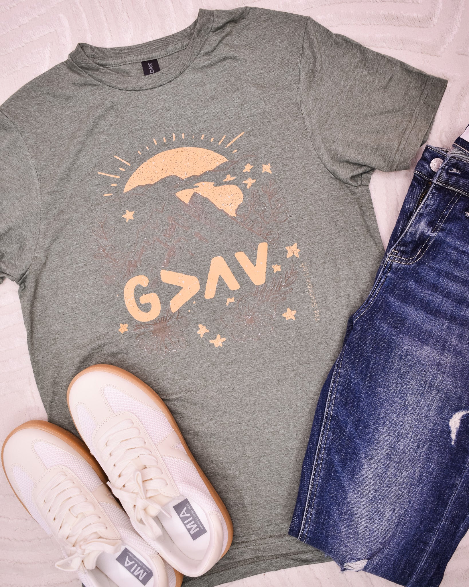 Gray t-shirt with 'G>AV' design, paired with jeans and sneakers on a light background