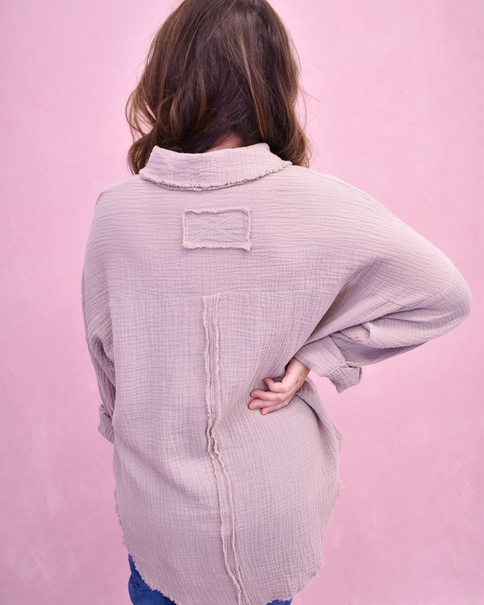 Person wearing a light purple textured shirt against a pink background