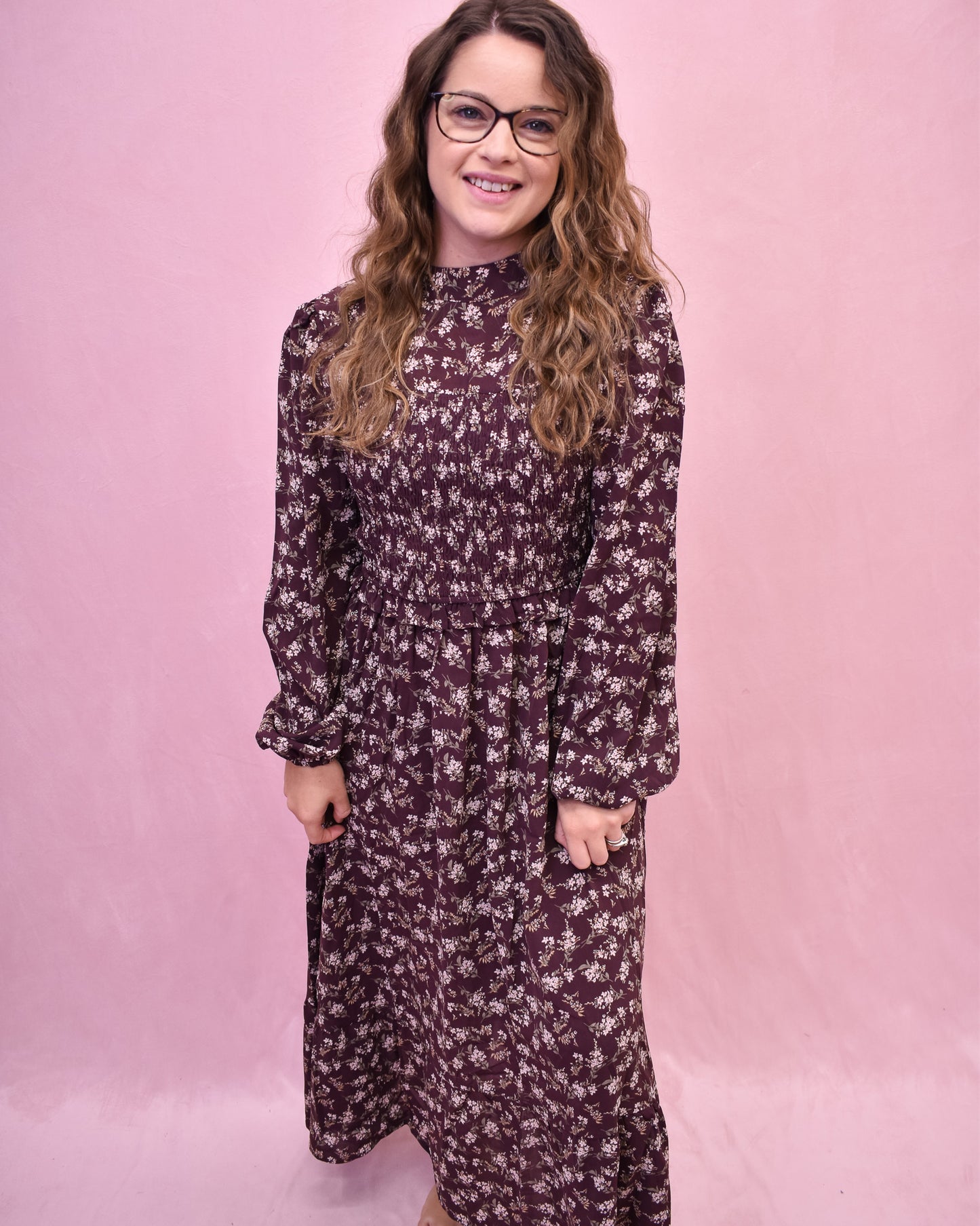 Woman wearing a floral dress against a pink background
