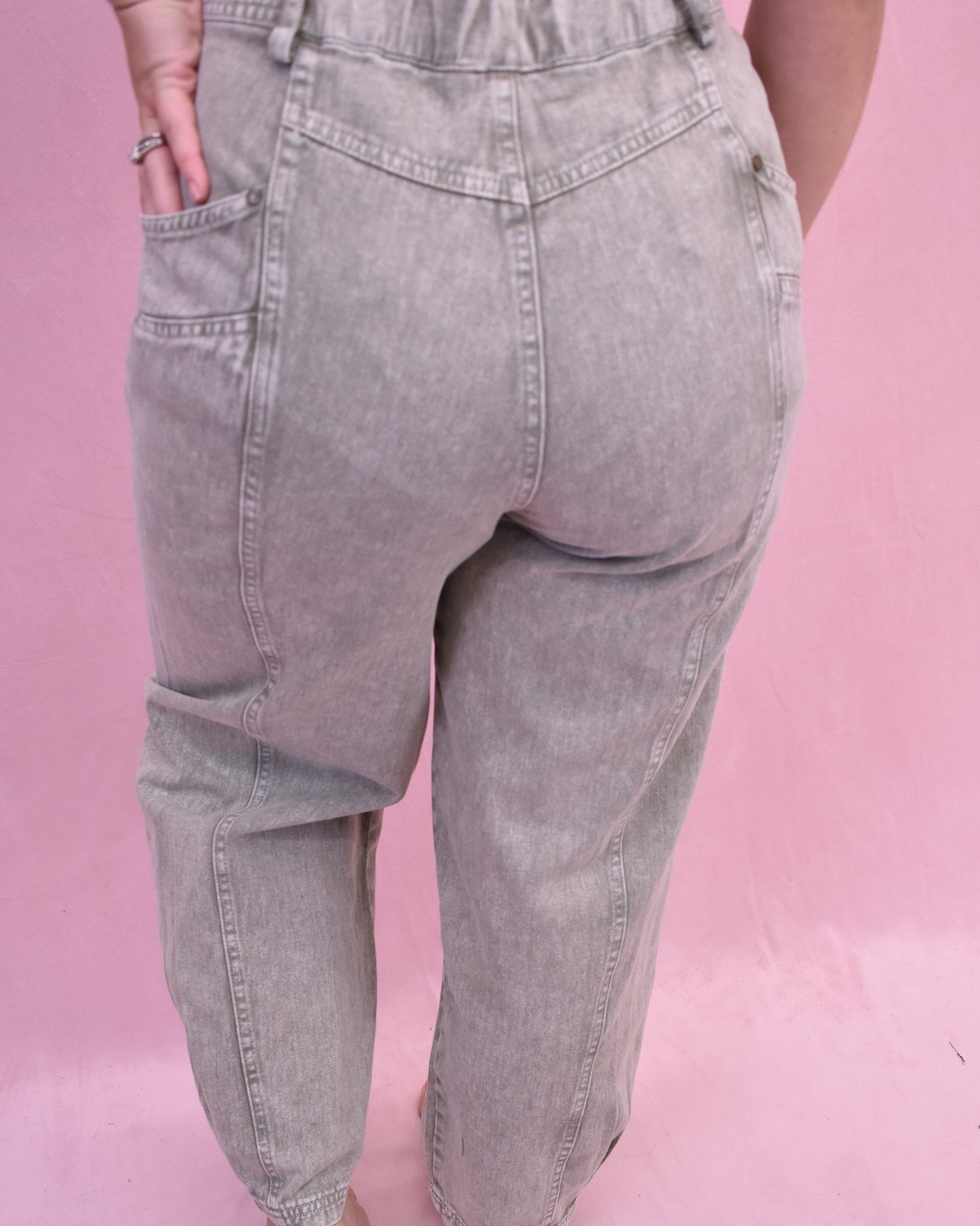 Gray jeans worn by a person on a pink background