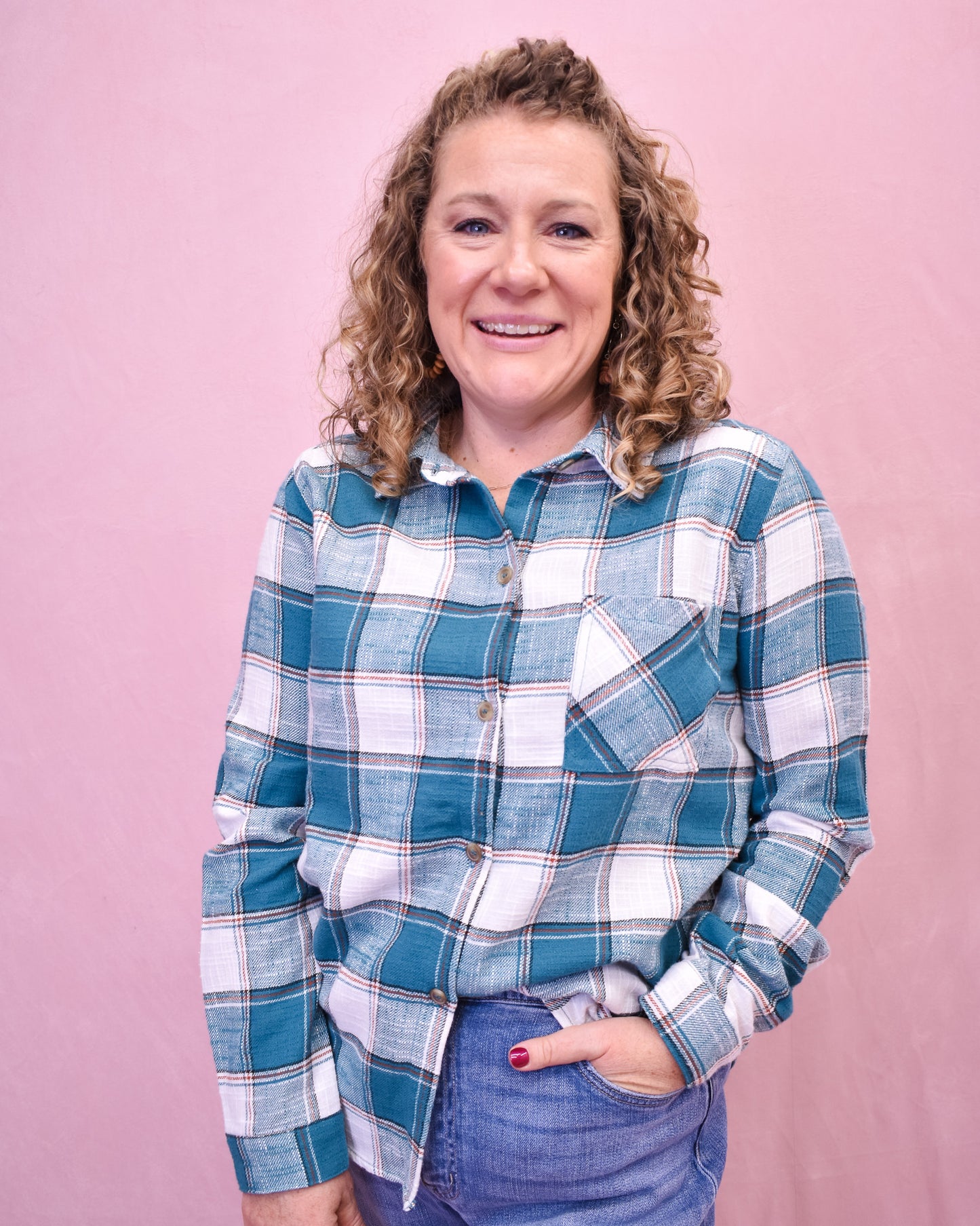 Woman wearing a blue and white plaid shirt against a pink background