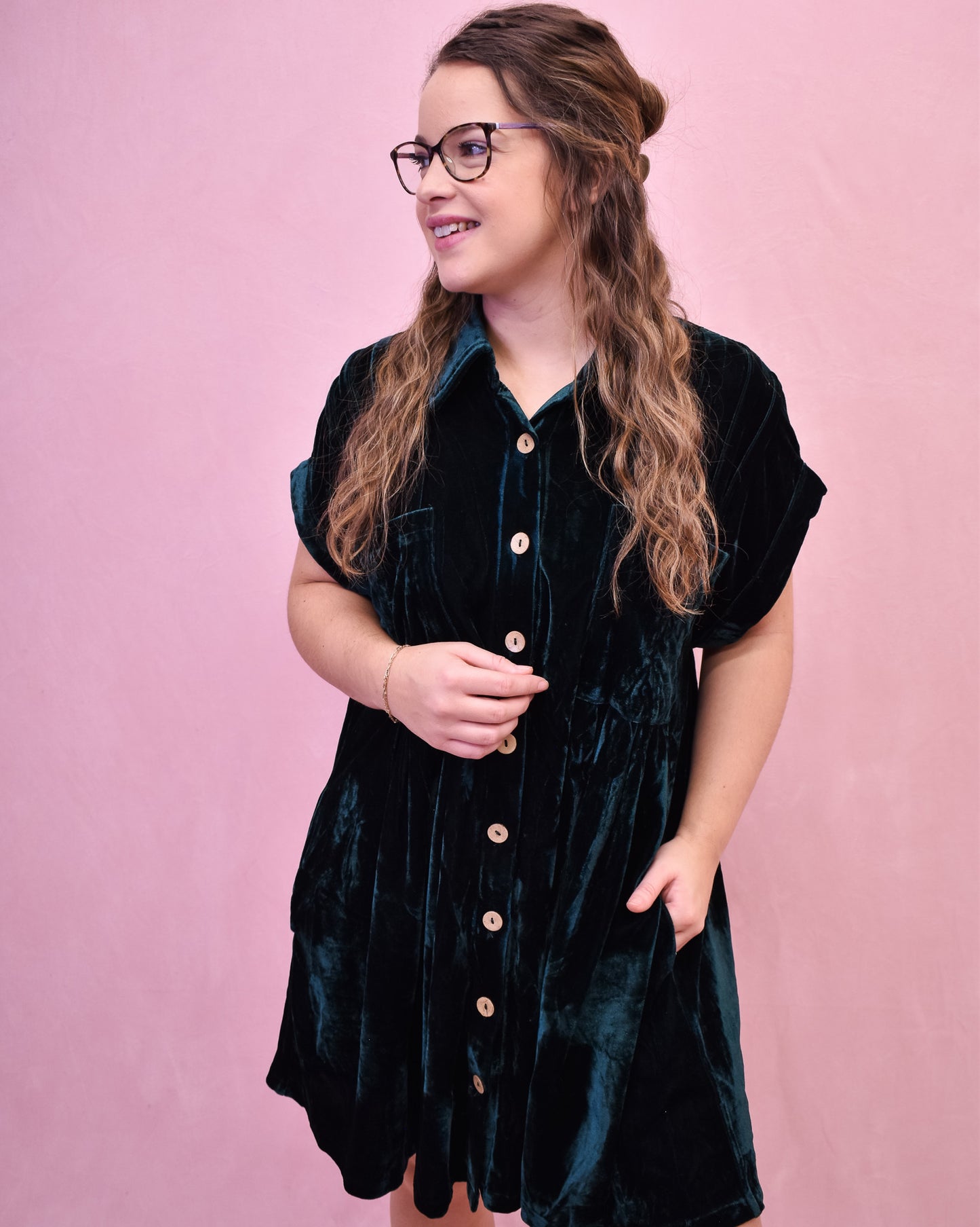 Woman wearing a black velvet dress with a pink background