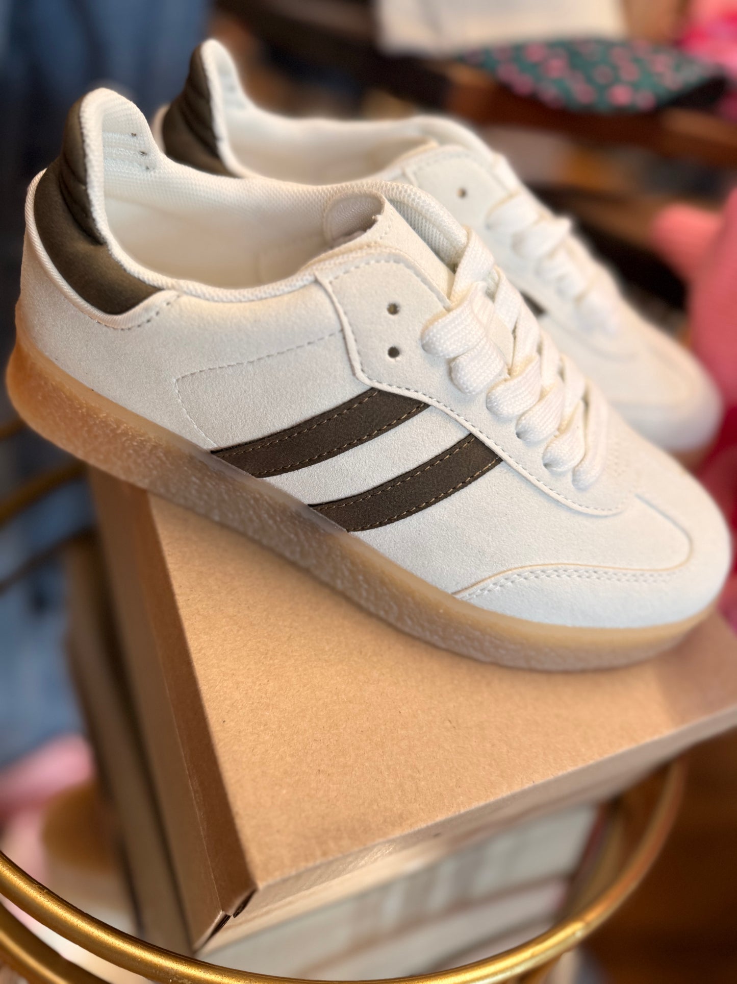 White sneakers with black stripes on a display stand