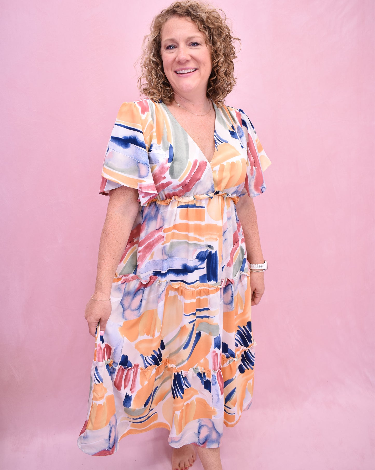 Woman wearing a colorful dress against a pink background