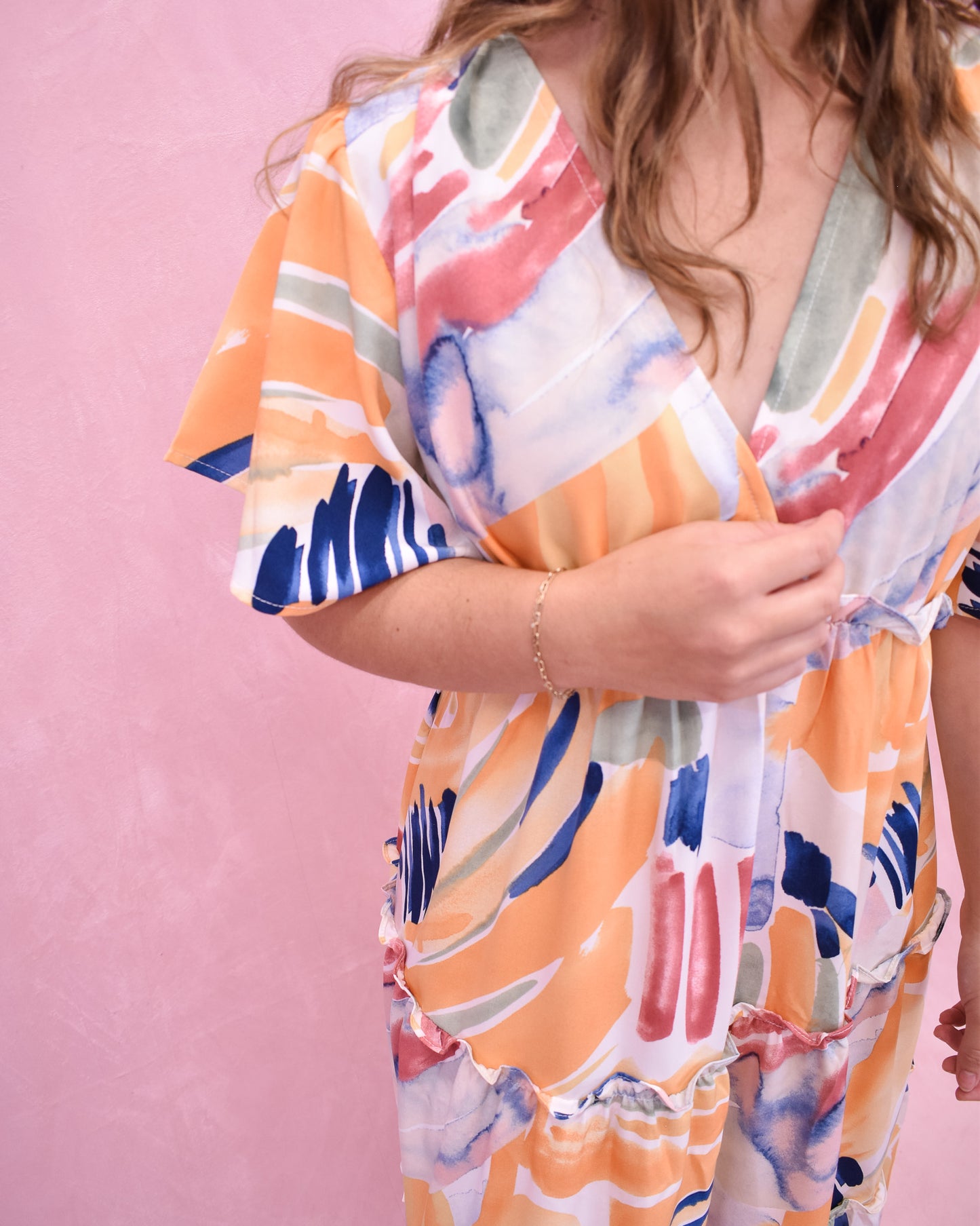 Woman wearing a colorful kimono-style garment against a pink background