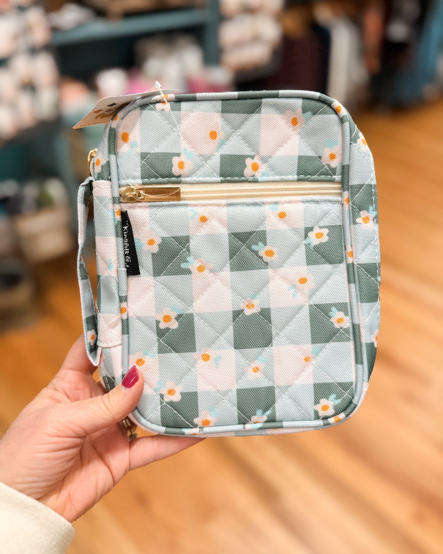 Quilted pouch with floral pattern held by a hand in an indoor setting