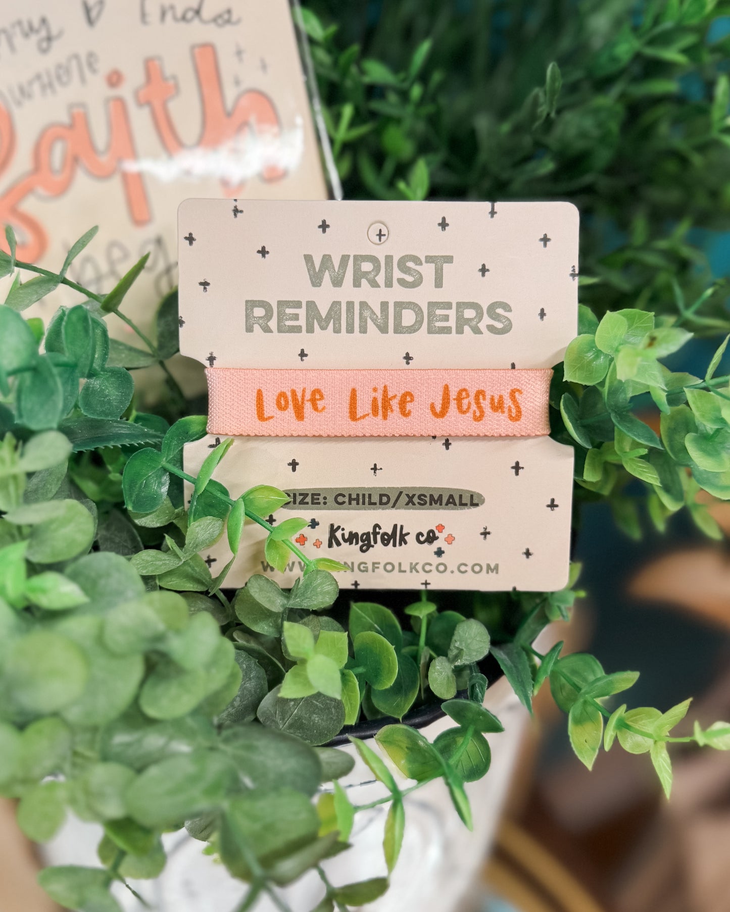Wrist reminder with 'Love Like Jesus' text on a green leafy background