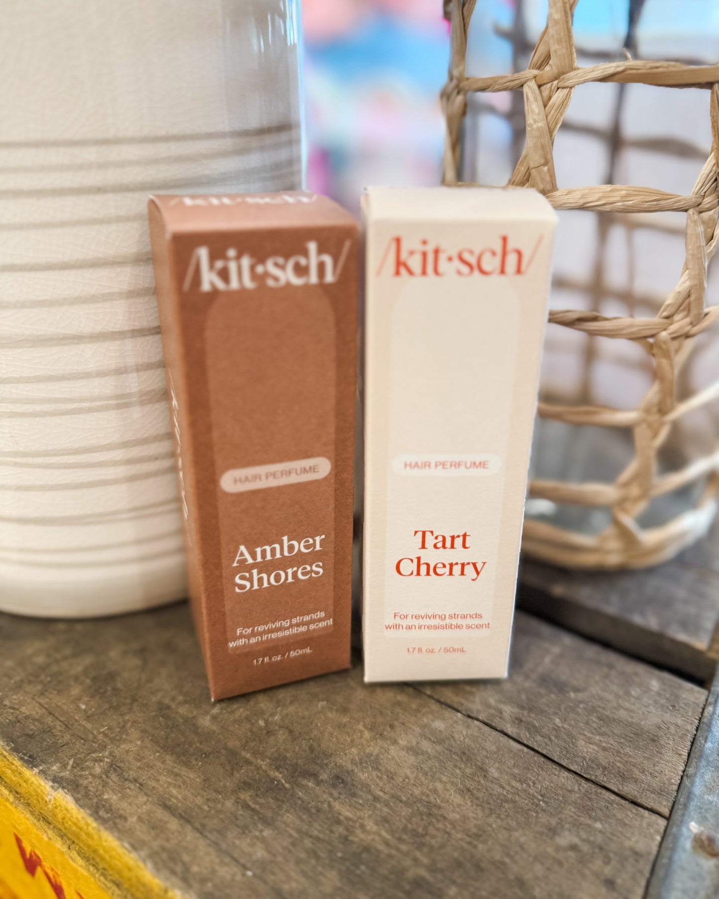 Two Kitsch perfume bottles on a wooden surface with a blurred background