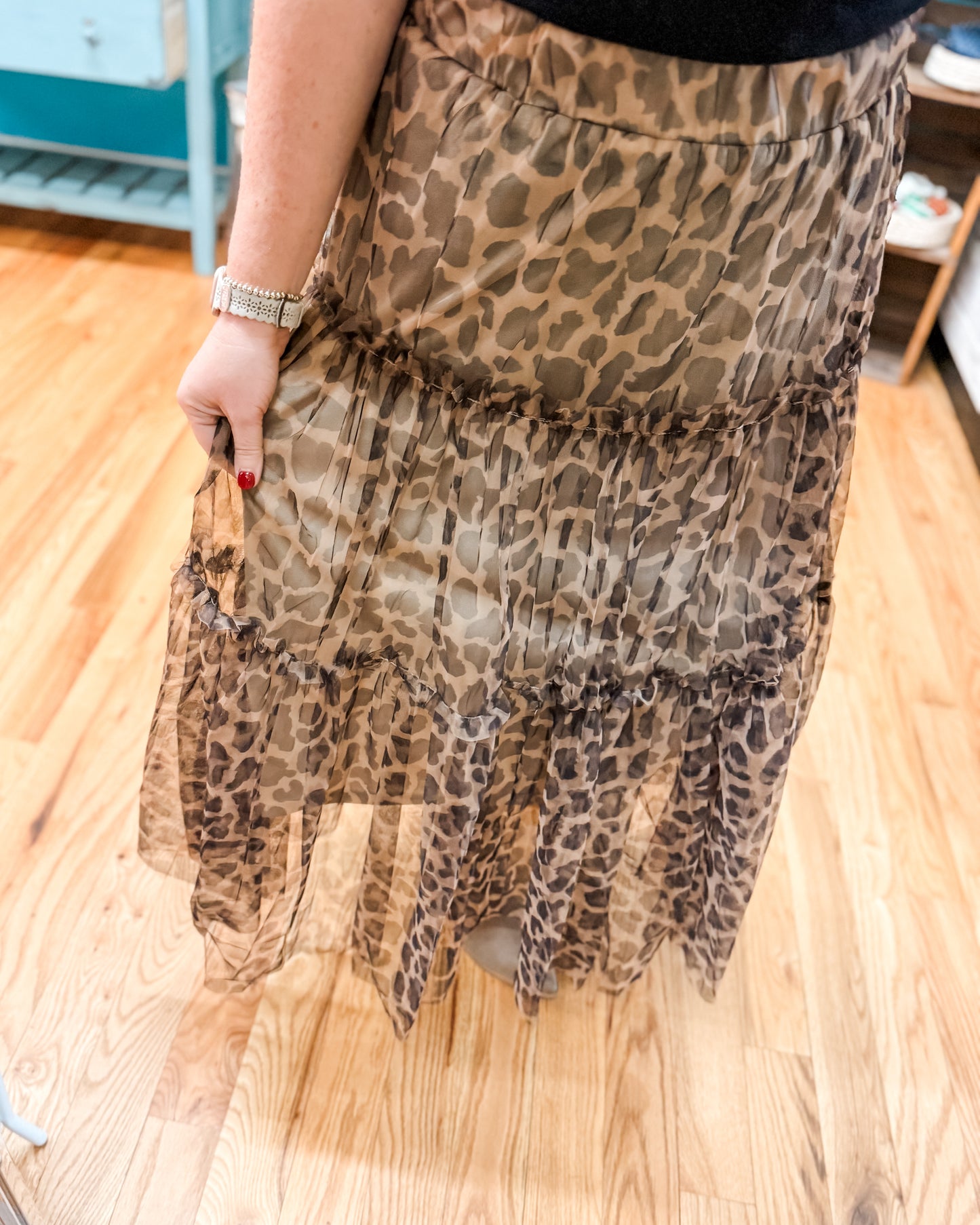 Leopard print skirt held by a person on a wooden floor