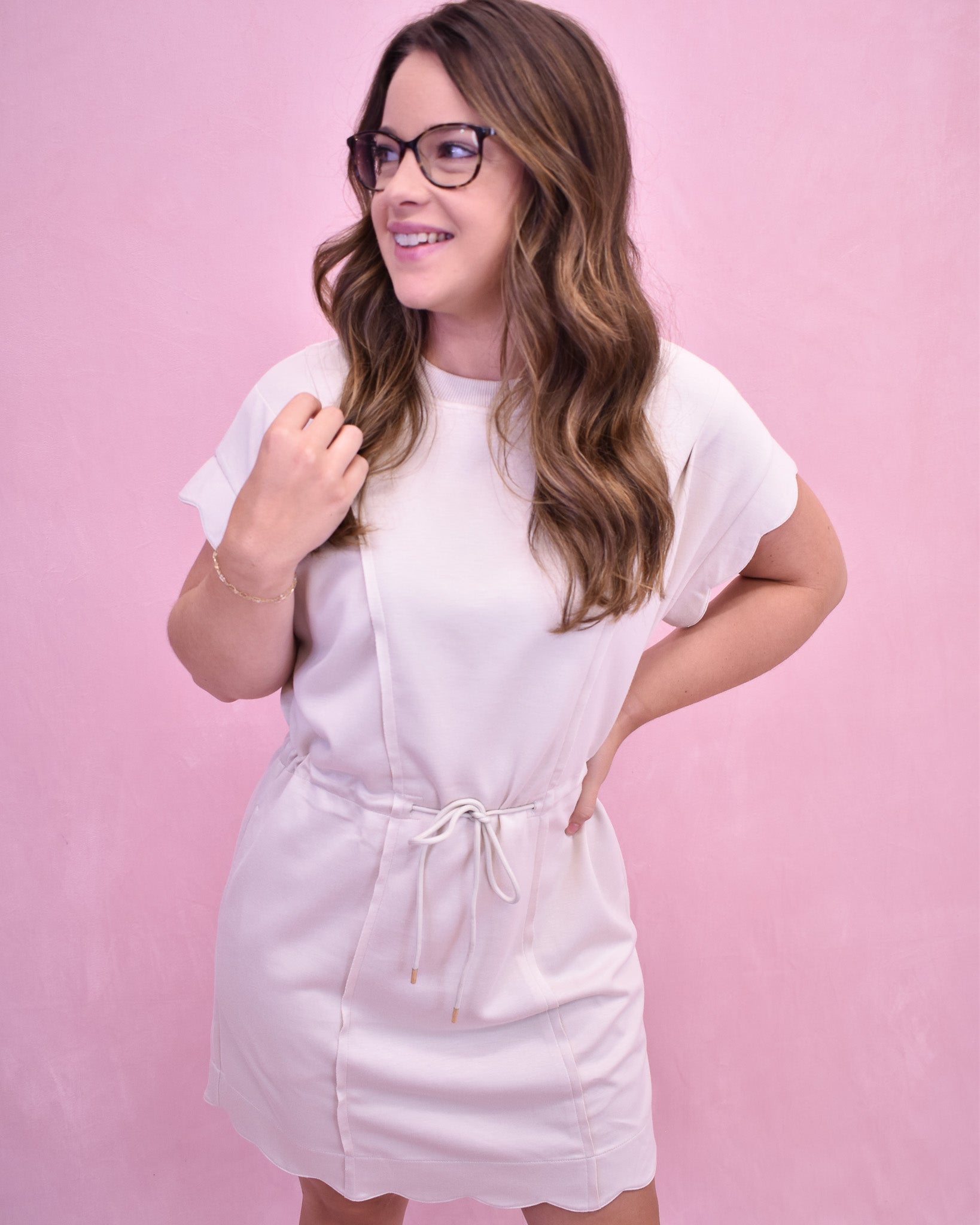 Woman wearing a white dress against a pink background
