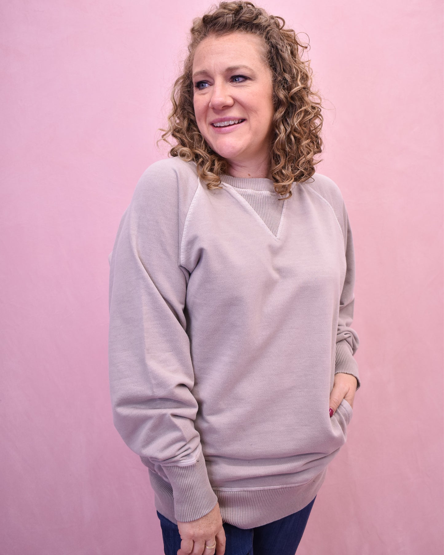 Woman wearing a light purple sweater against a pink background