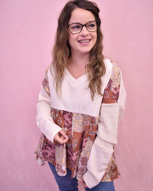 Woman wearing a white and patterned long-sleeve top against a pink background