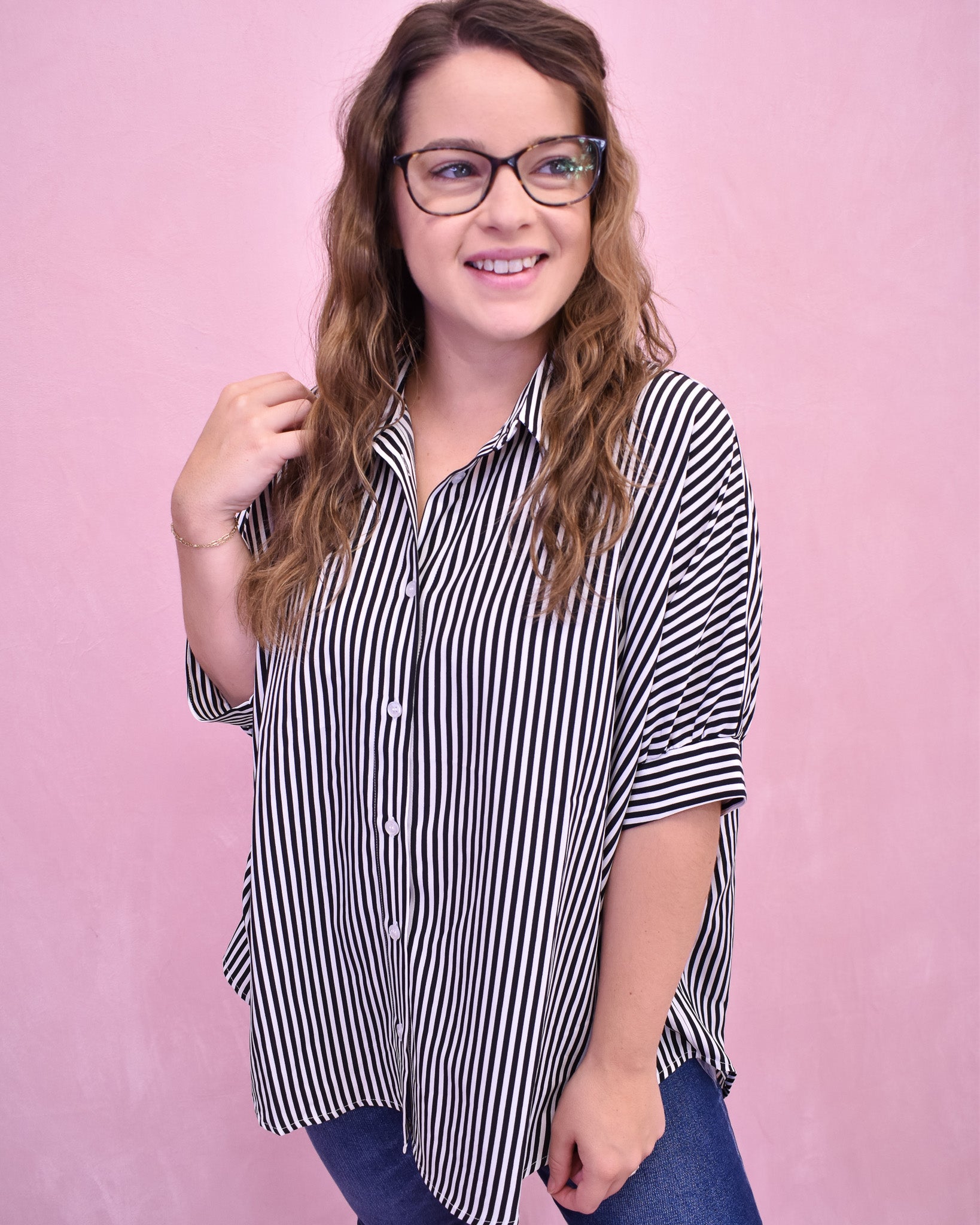 Woman wearing a black and white striped shirt against a pink background