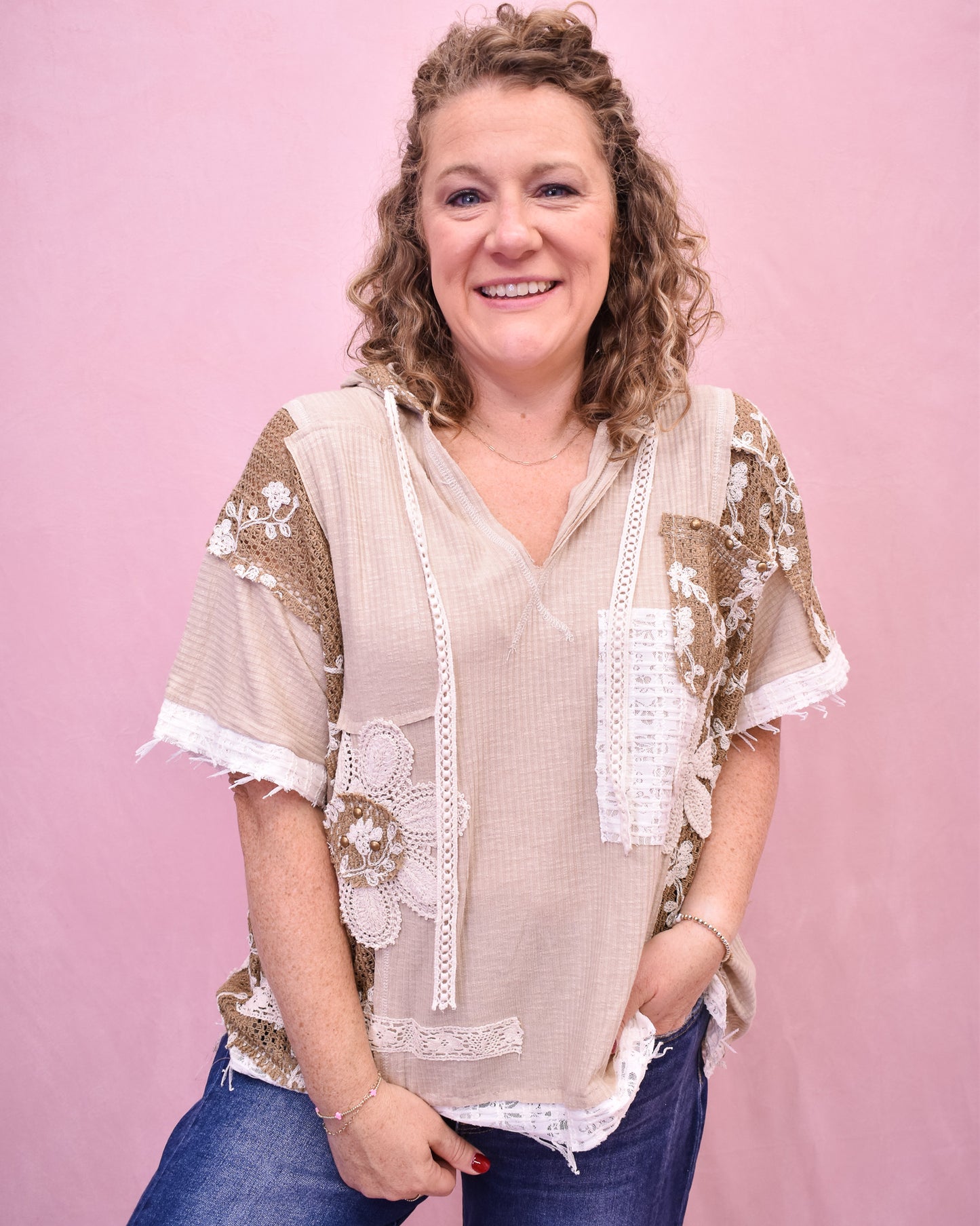 Woman wearing a beige lace blouse against a pink background