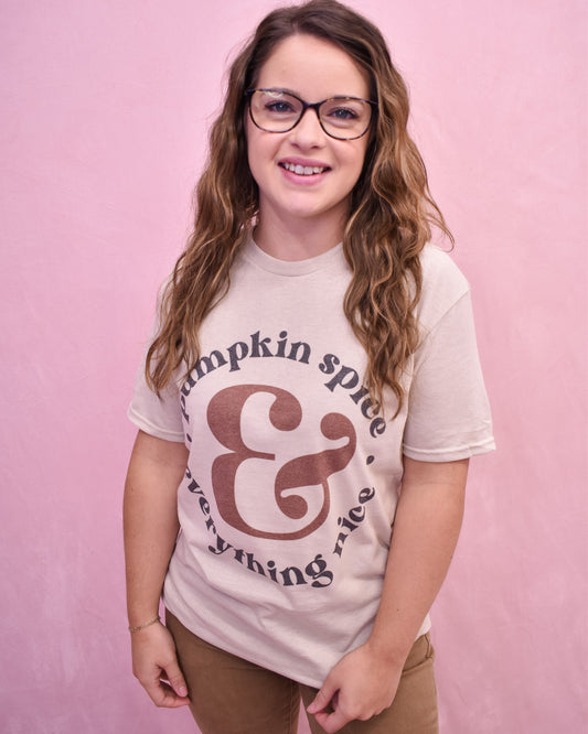 Person wearing a 'Pumpkin spice & everything nice' t-shirt against a pink background