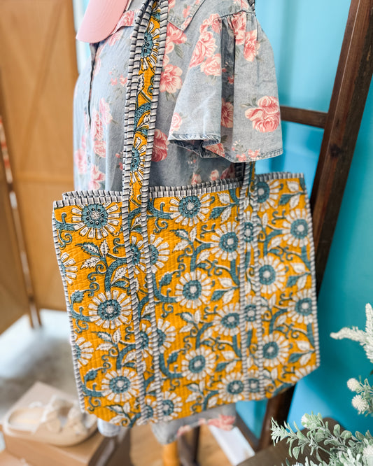 Patterned bag with a floral design held by a person against a blue wall.
