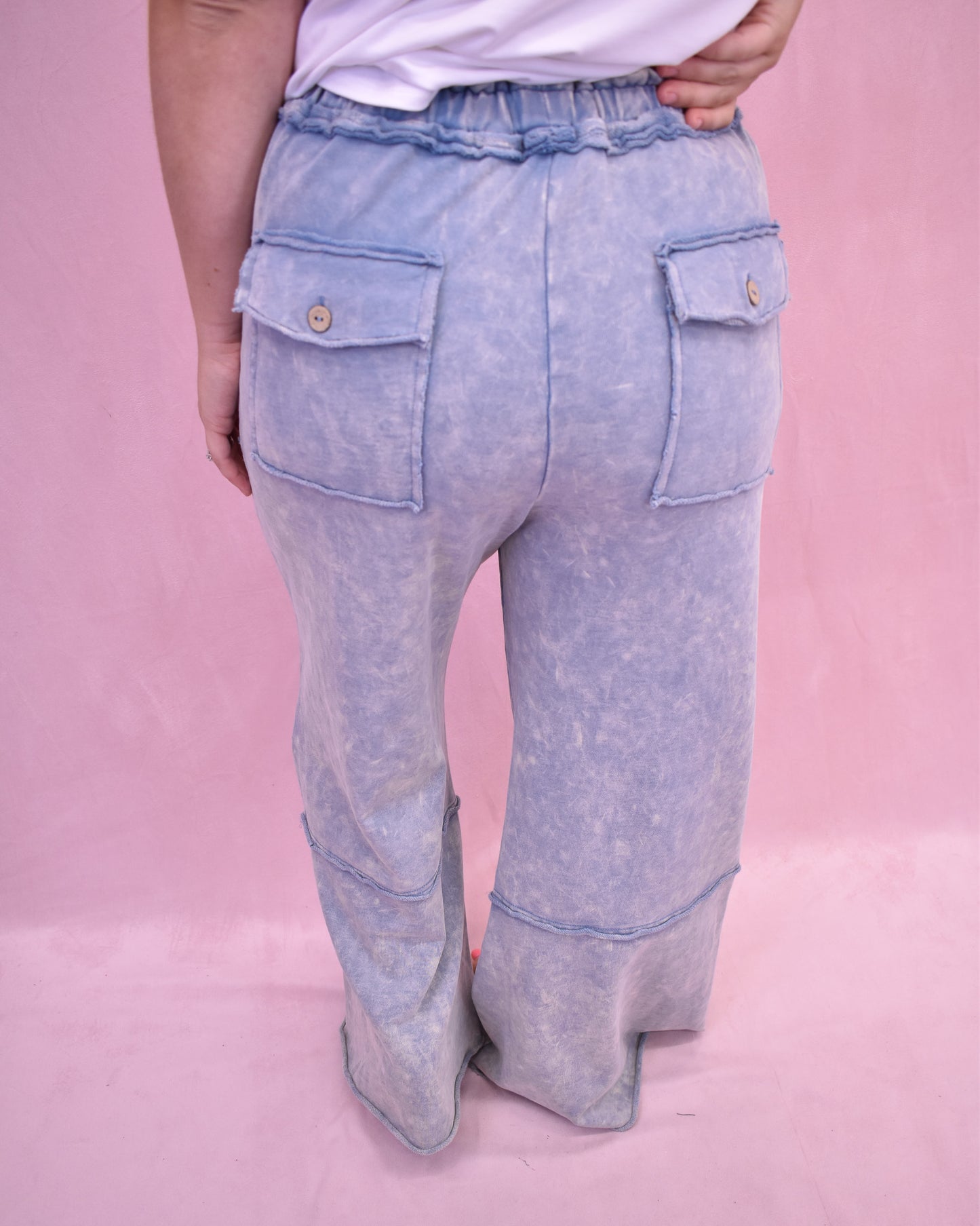 Light blue denim pants with front pocket design on a pink background