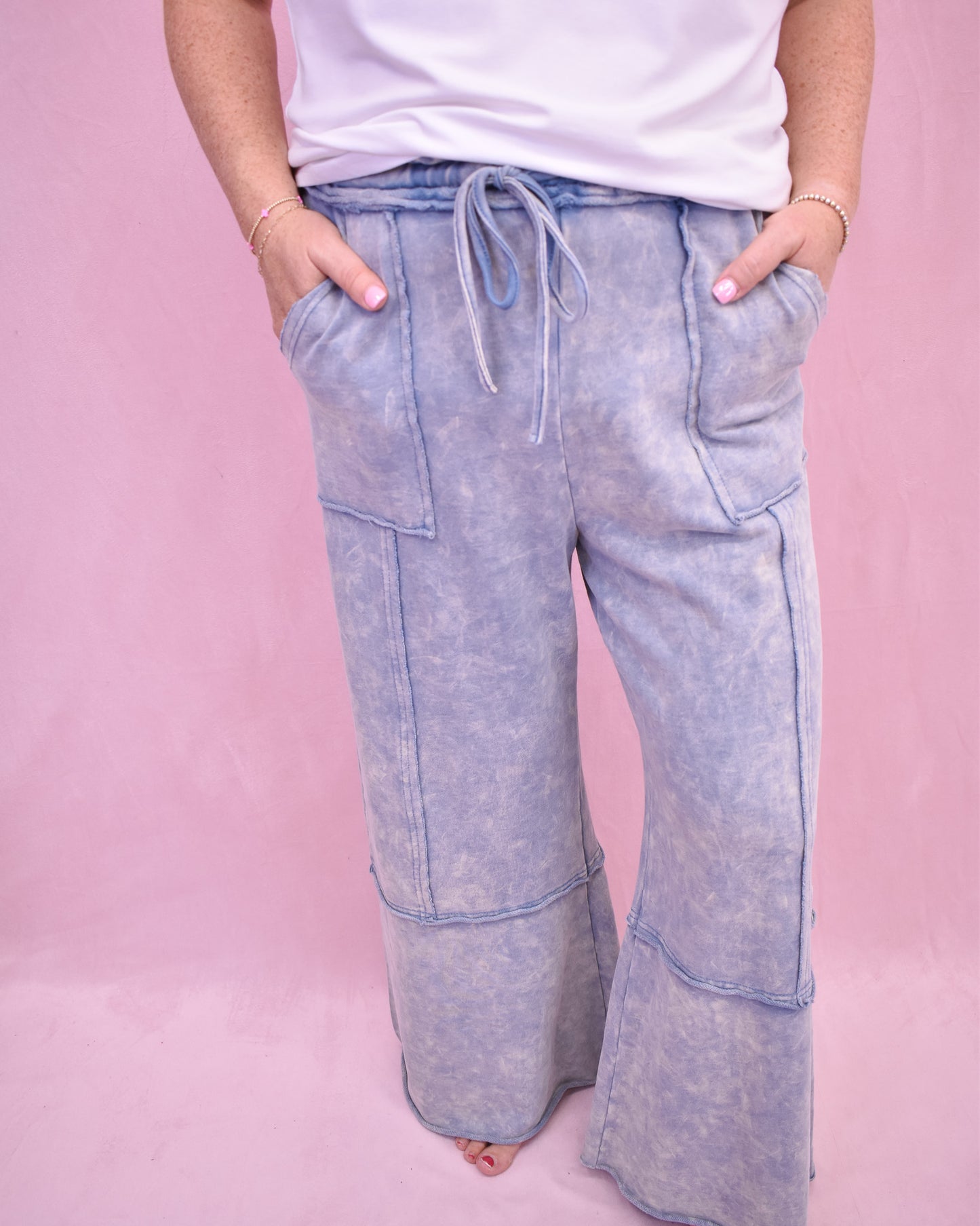 Light blue acid-wash pants worn by a person on a pink background