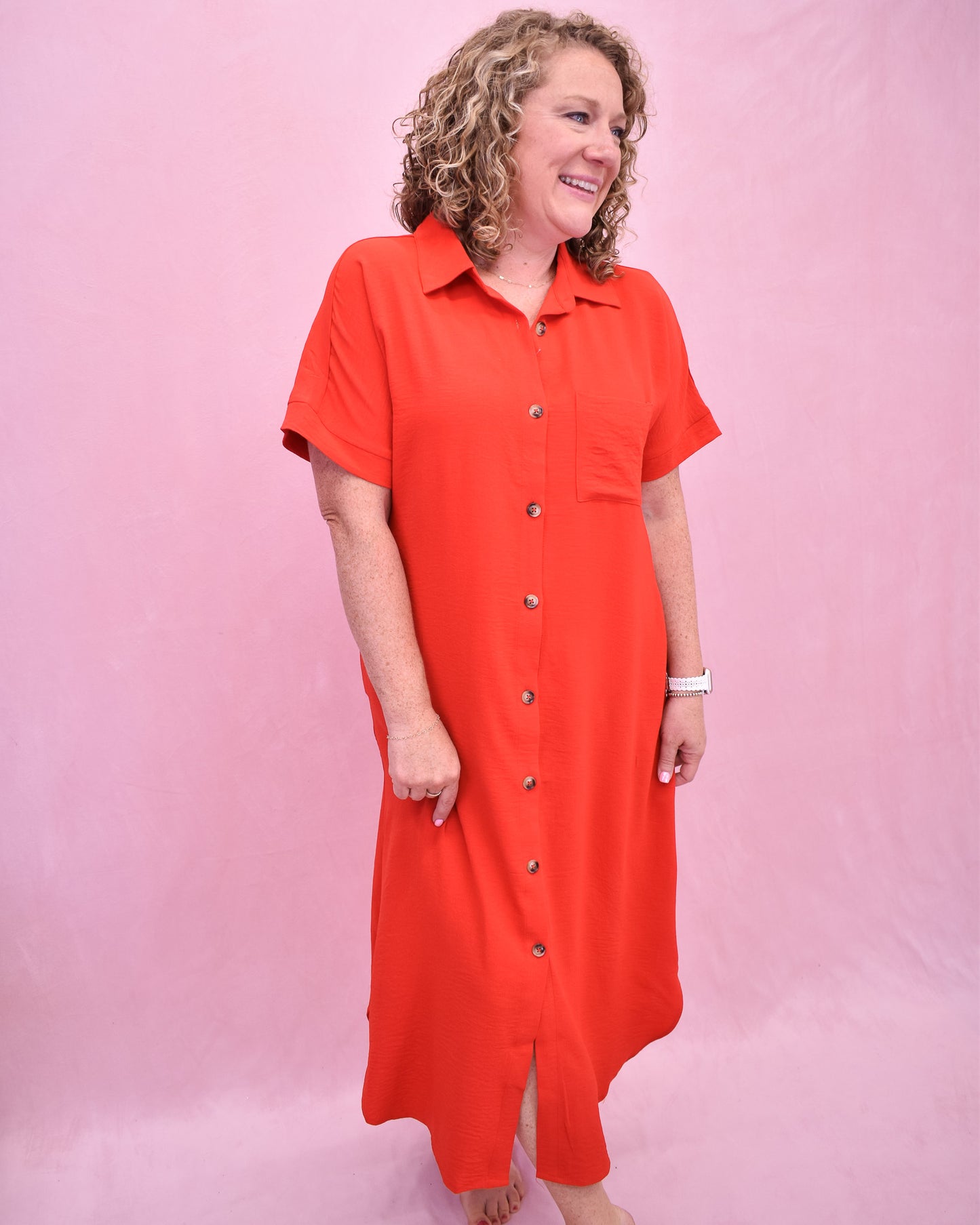 Woman wearing a red dress with buttons on a pink background