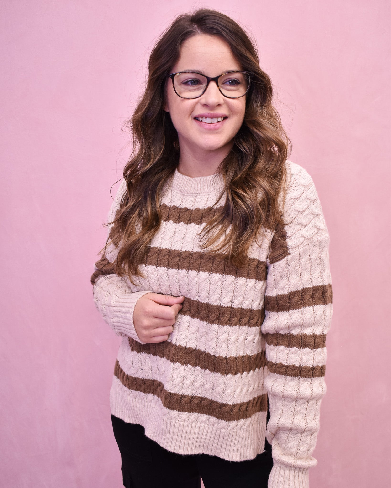 Woman wearing a striped sweater against a pink background
