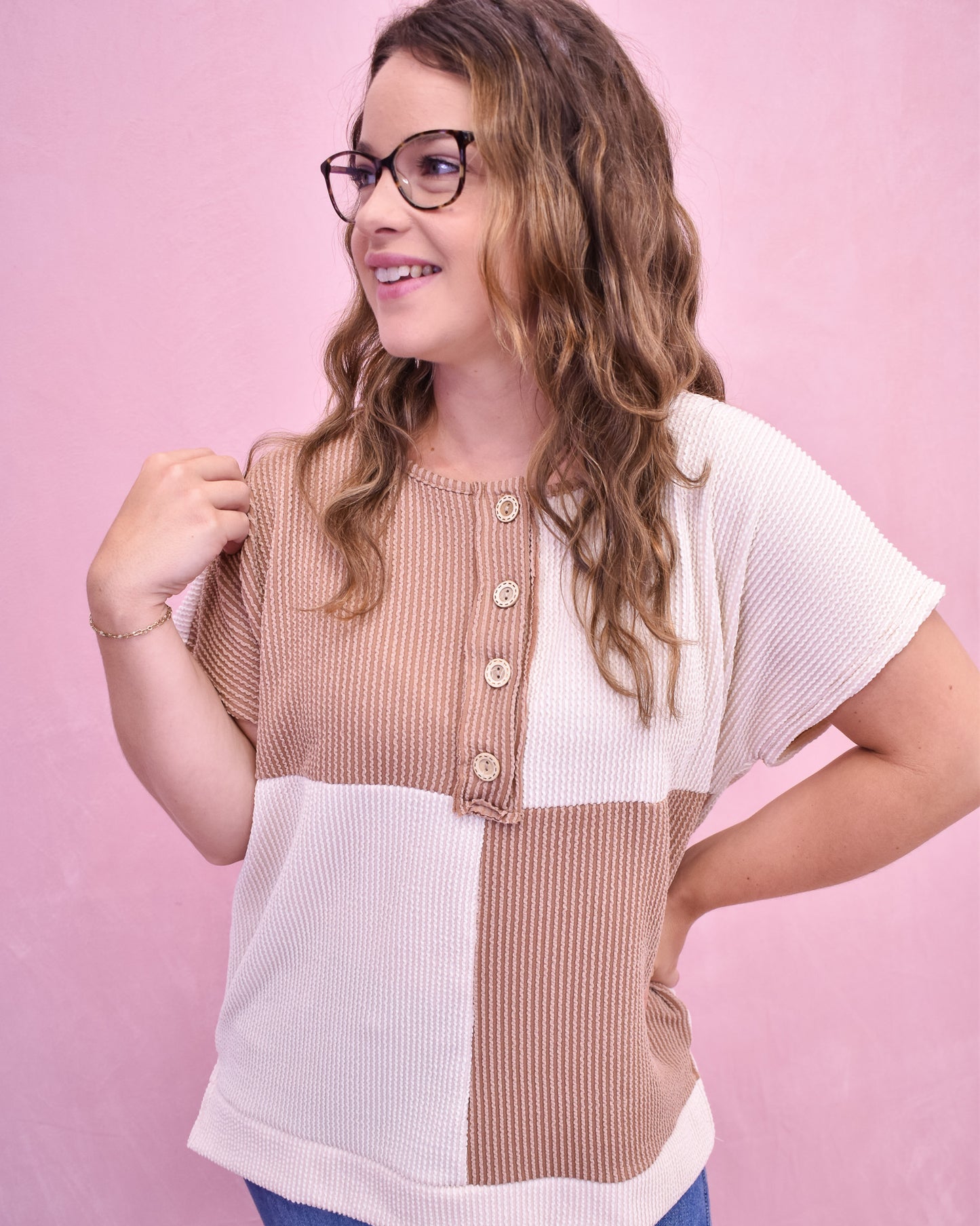 Woman wearing a two-tone top with a pink background