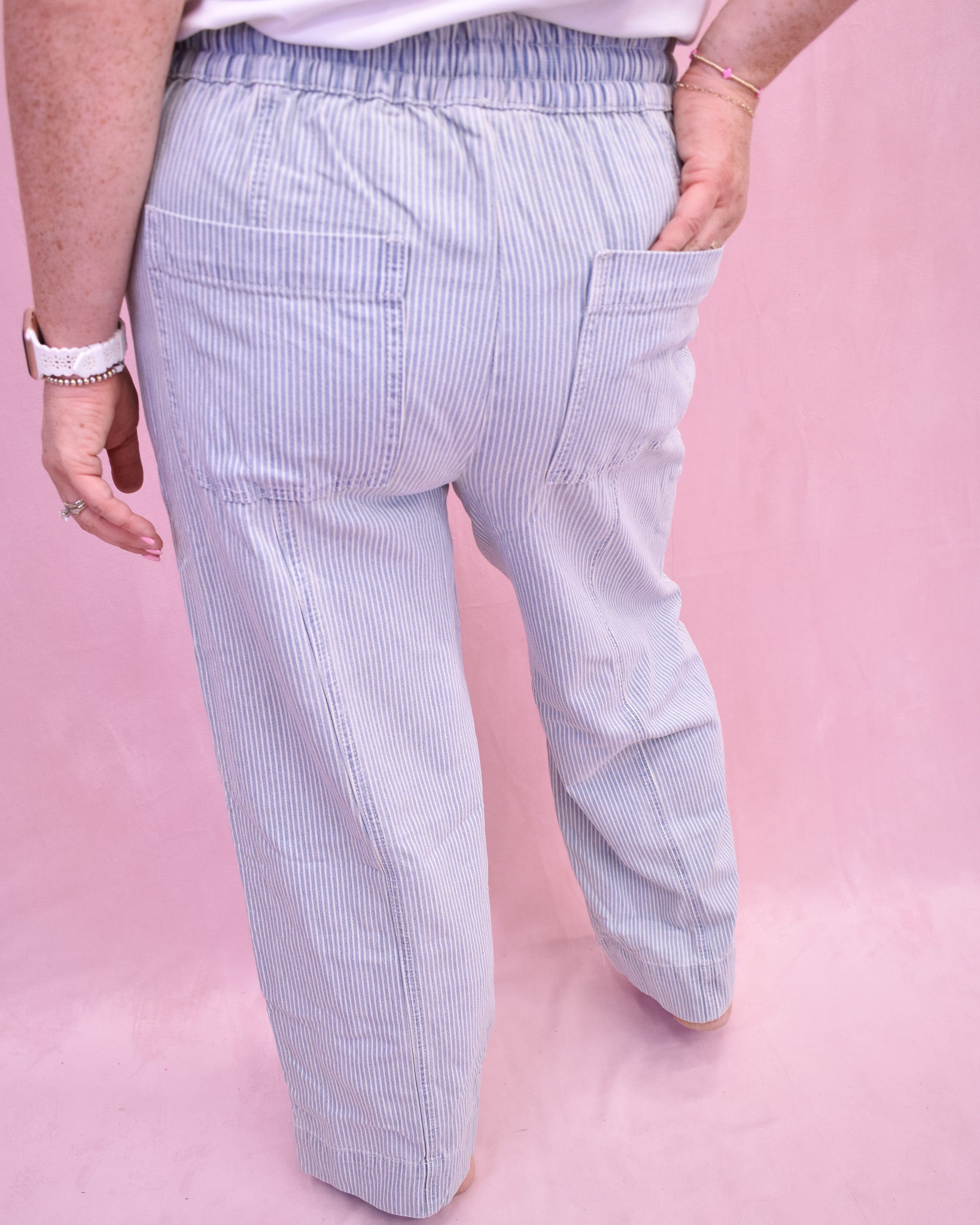 Light blue striped pants worn by a person on a pink background
