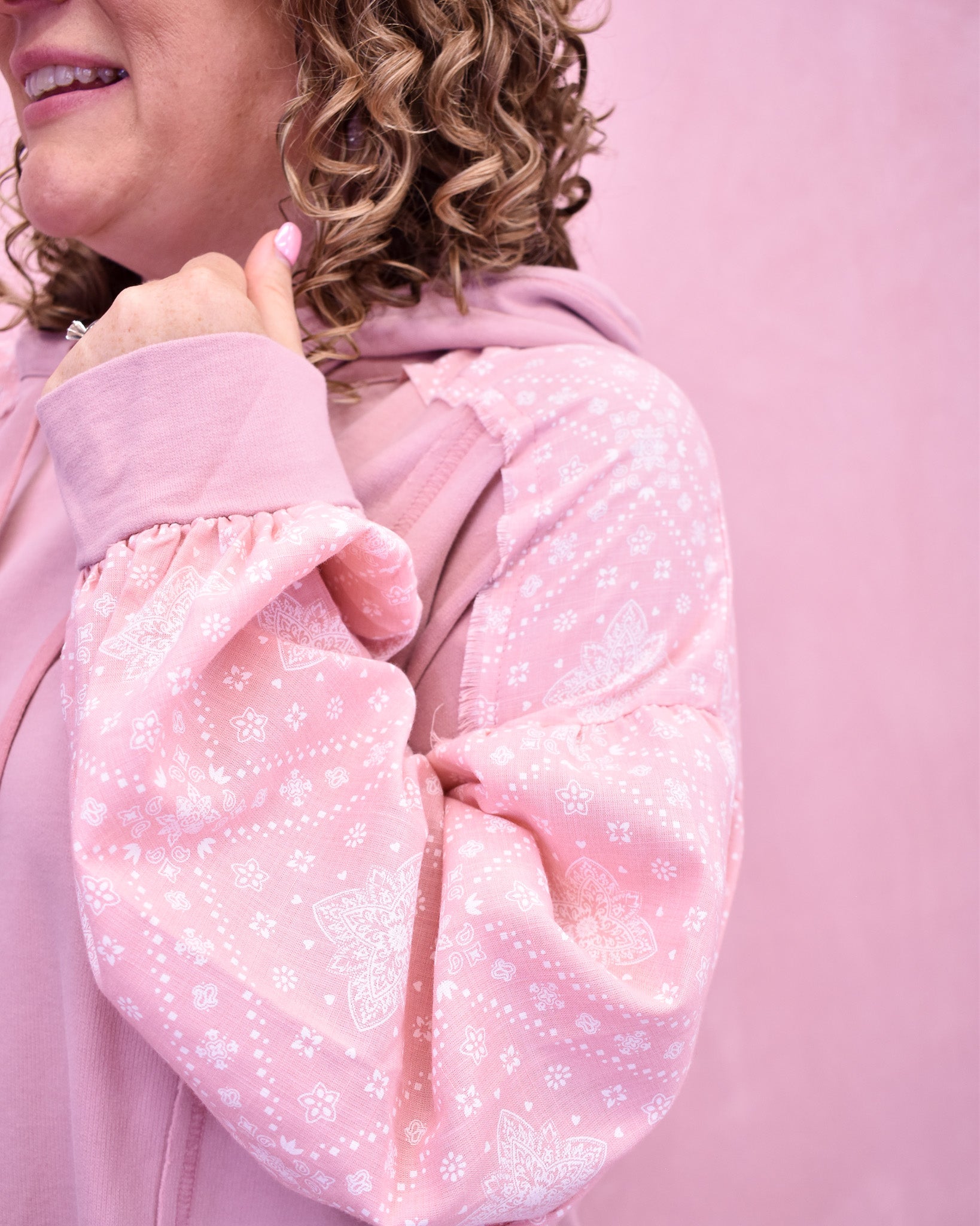 Person wearing a pink outfit with floral patterns on a pink background