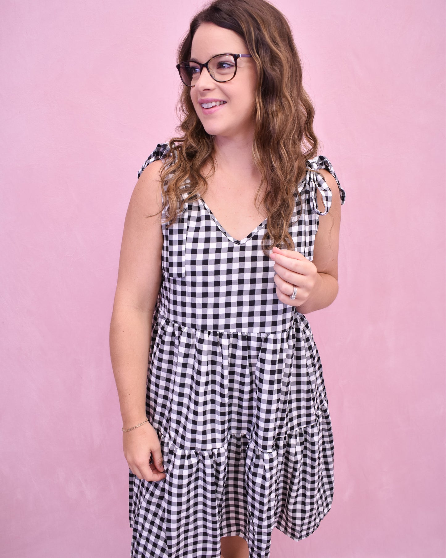 Woman wearing a black and white checkered dress against a pink background