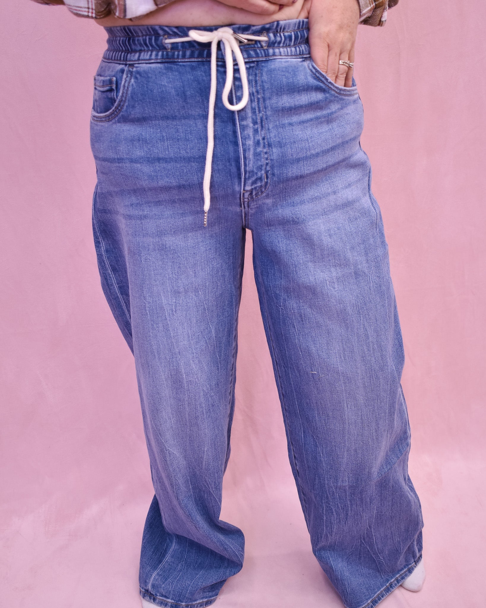 Blue jeans with a drawstring on a pink background