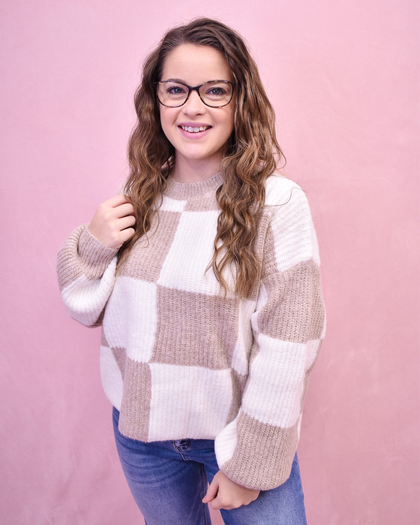 Woman wearing a checkered sweater against a pink background