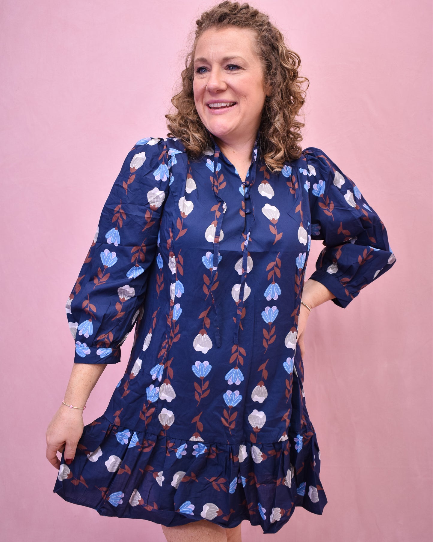 Woman wearing a blue floral dress against a pink background