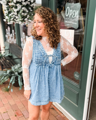 a sleeveless denim romper with pleated vneck, tie front, and pearls all over. paired with a lace layering top.