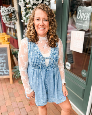 a sleeveless denim romper with pleated vneck, tie front, and pearls all over. paired with a lace layering top.